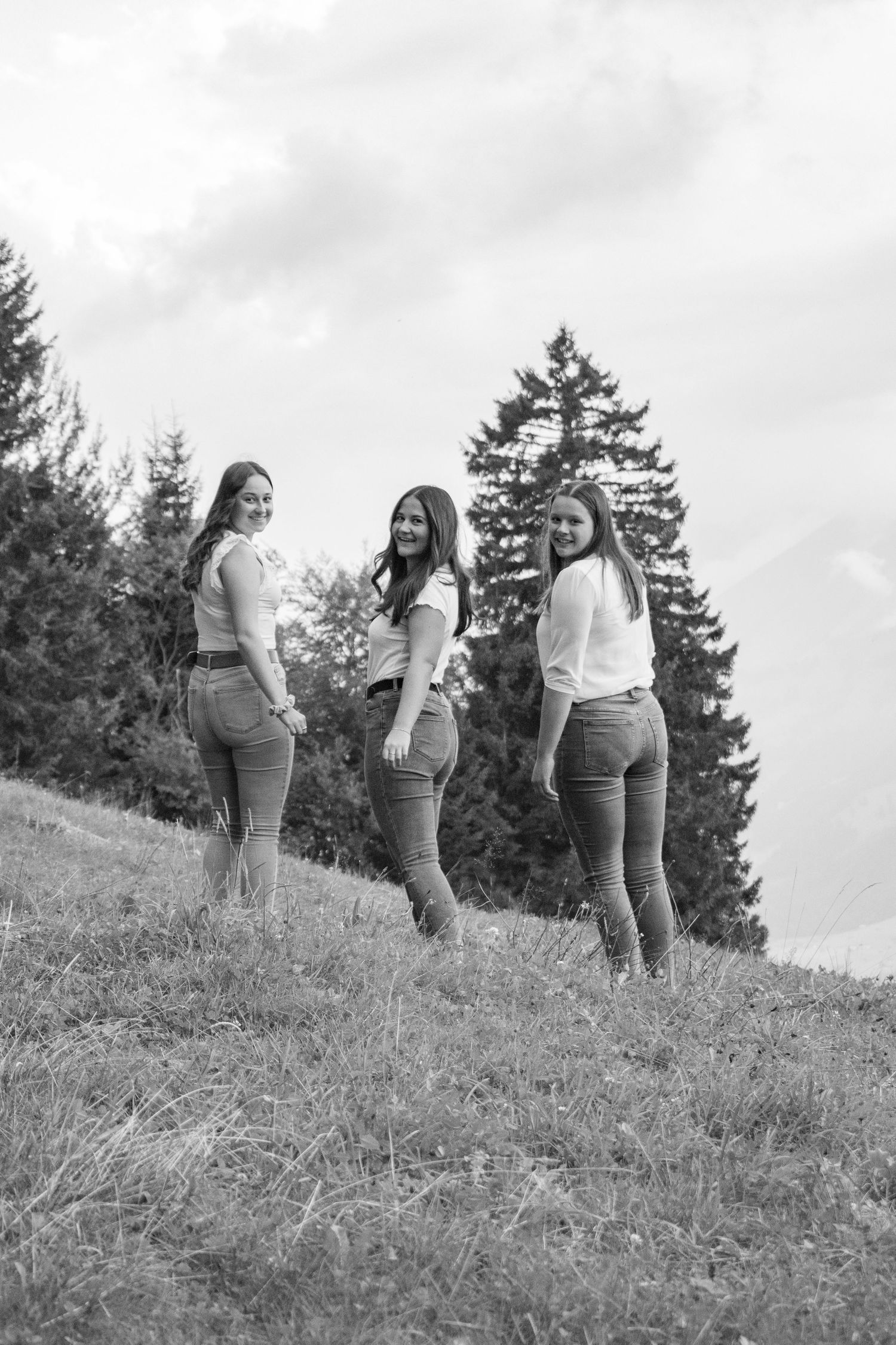 Three friends walking together on grassy hillside in black and white.