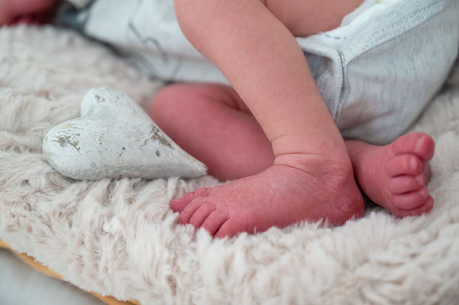 Close-up view of tiny baby feet resting on soft white fabric.