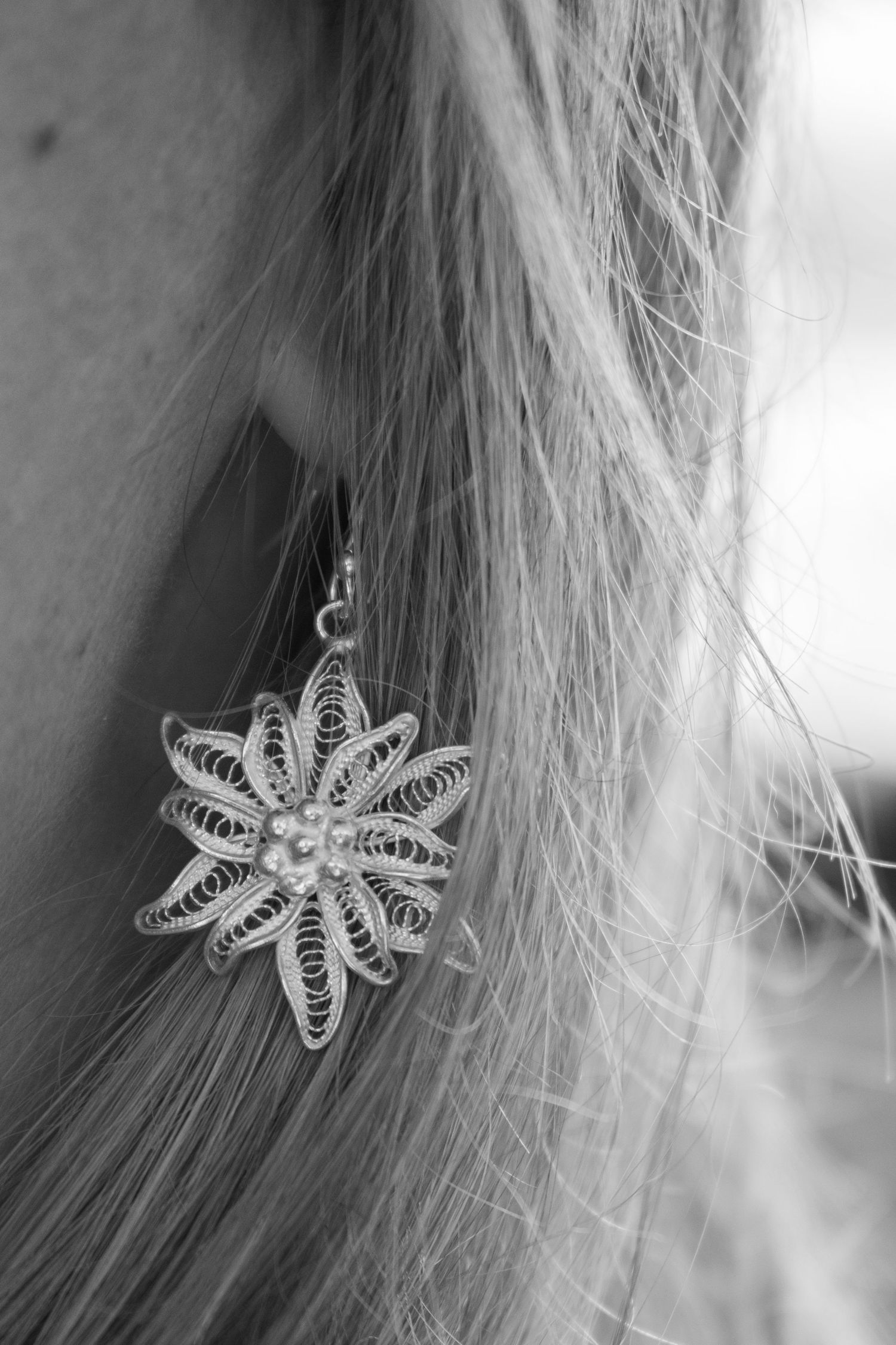 Close-up shots of delicate white filigree flower hair accessories against a blurred background.