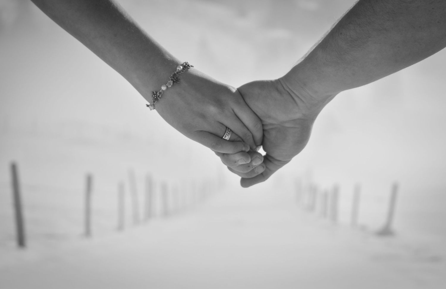 Black and white close-up of two hands clasped together against blurred background.