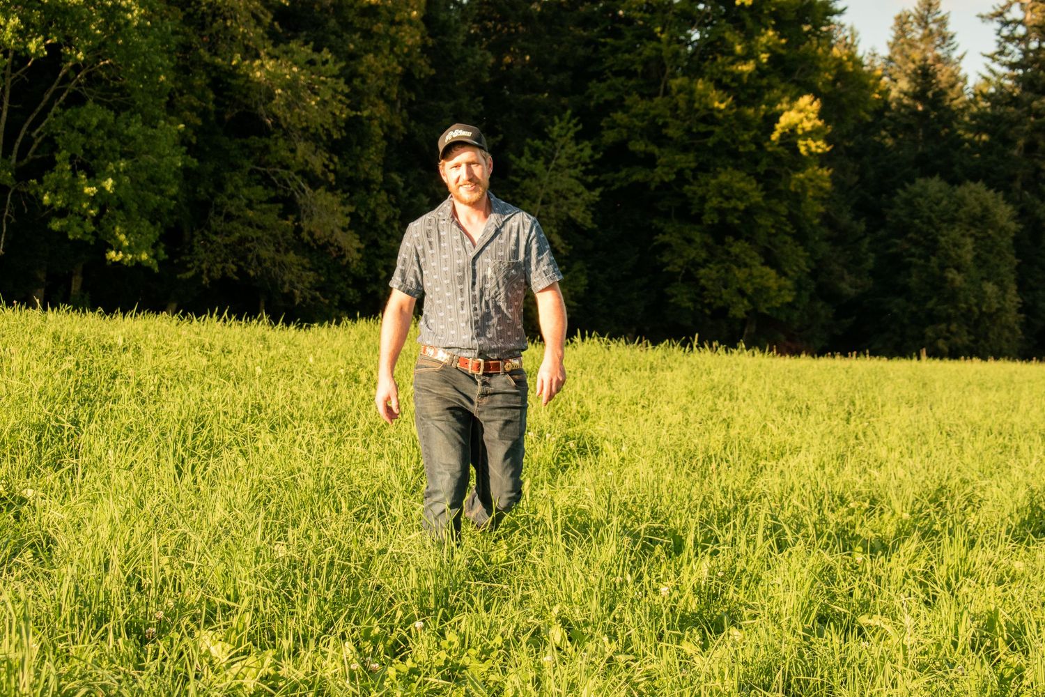 Person standing in sunlit meadow wearing casual clothing.