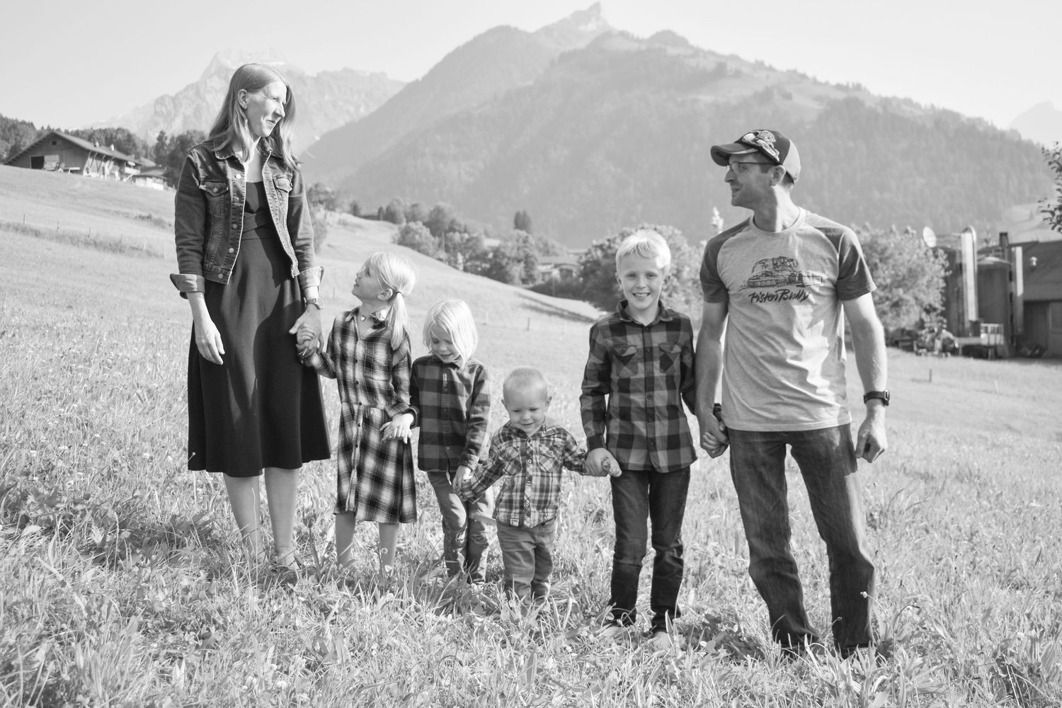Group walking together across grassy field with mountains in background.