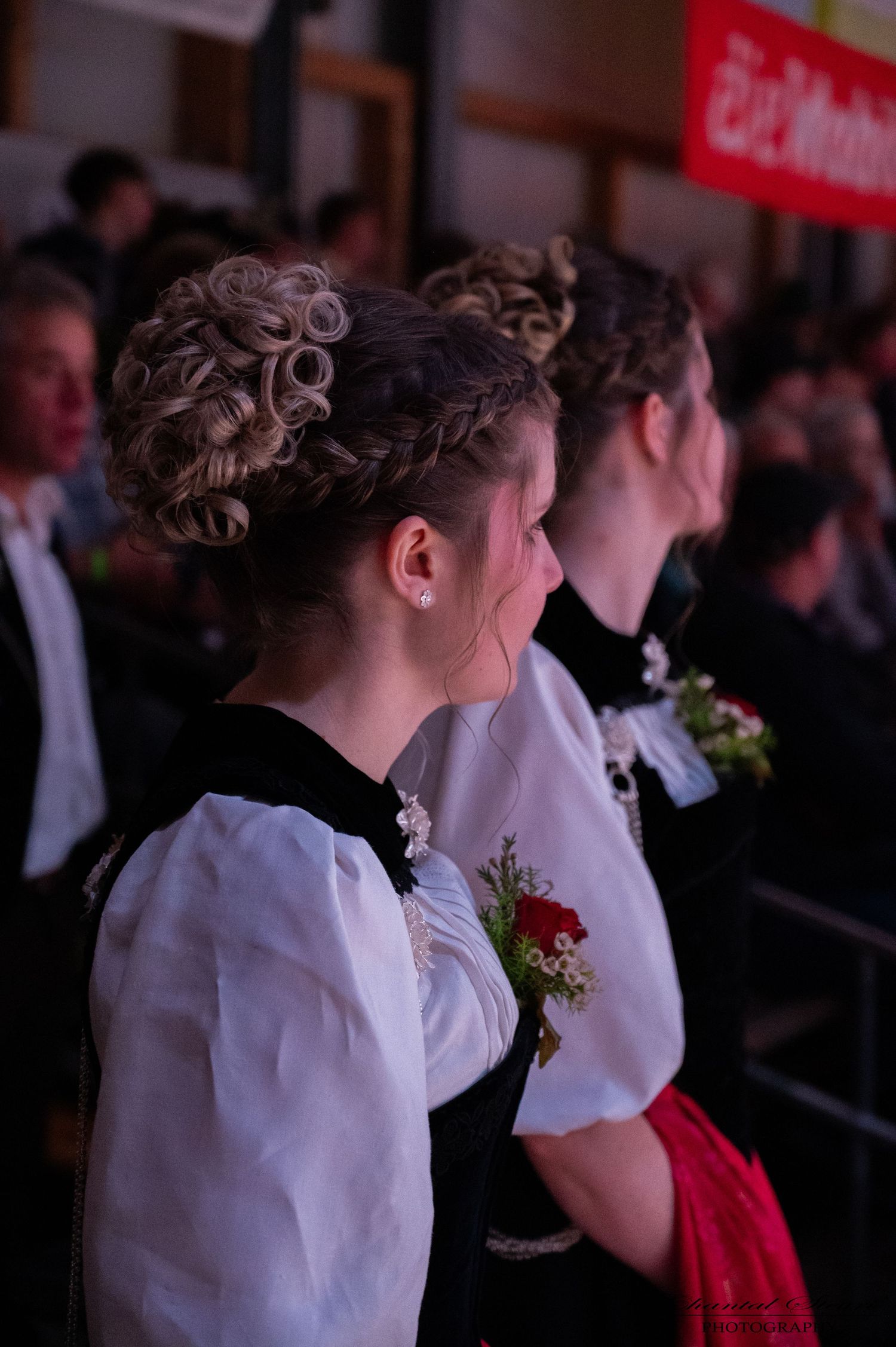 Exhibitors in white shirts and traditional dress watching cattle at a dairy show.