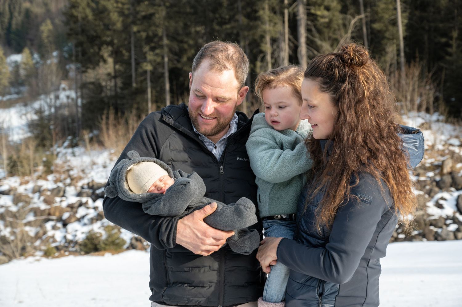Winter family scene with snow-covered forest in the background.