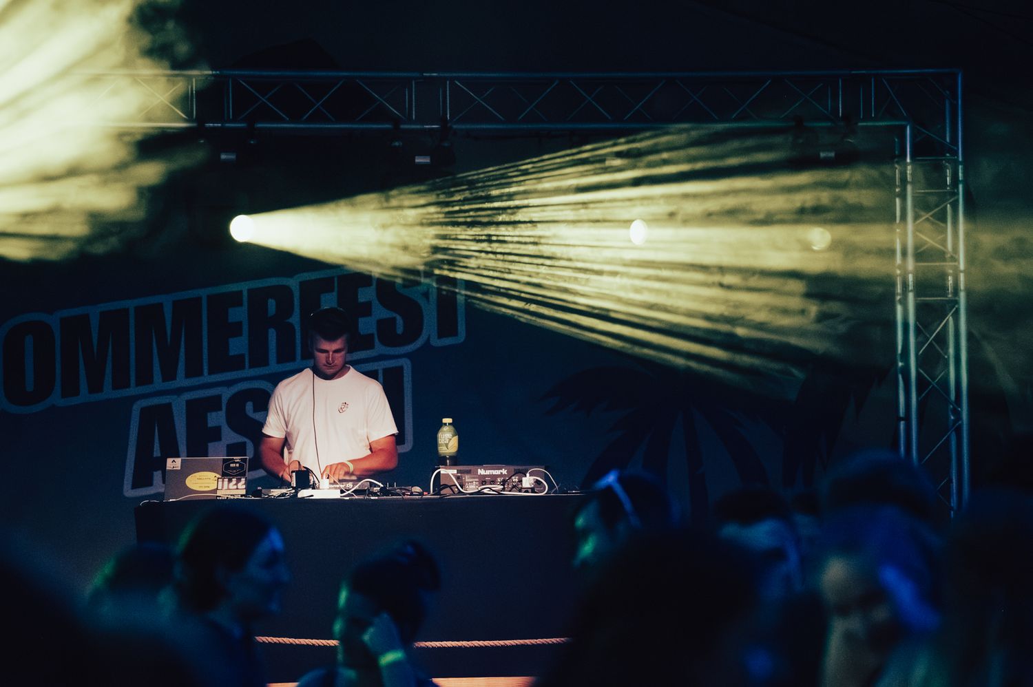 DJ performing on stage at Sommerfest festival with dramatic light beams illuminating the night sky.