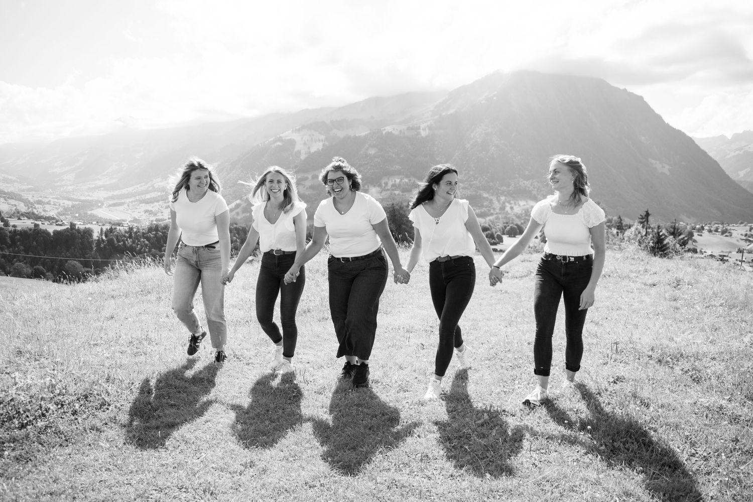 Group of friends holding hands while walking together in a scenic mountain landscape.