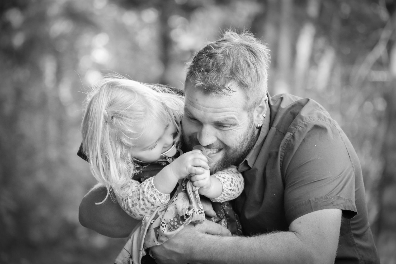 Intimate black and white portrait of a couple sharing a tender moment outdoors.