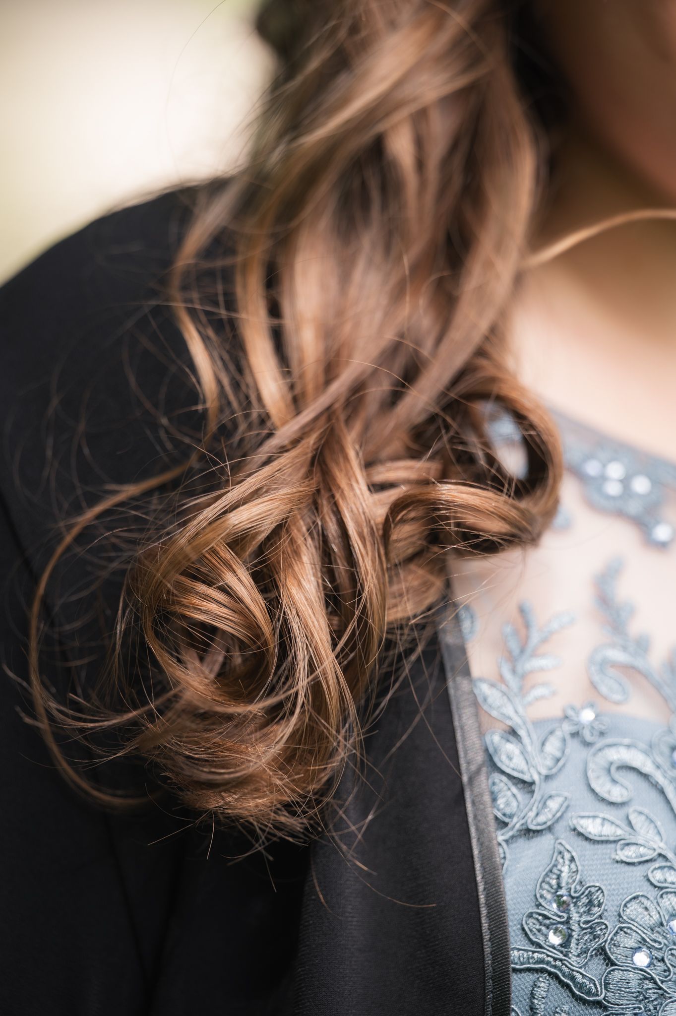Close-up of curly brown hair resting on a lace embroidered blue and black outfit.