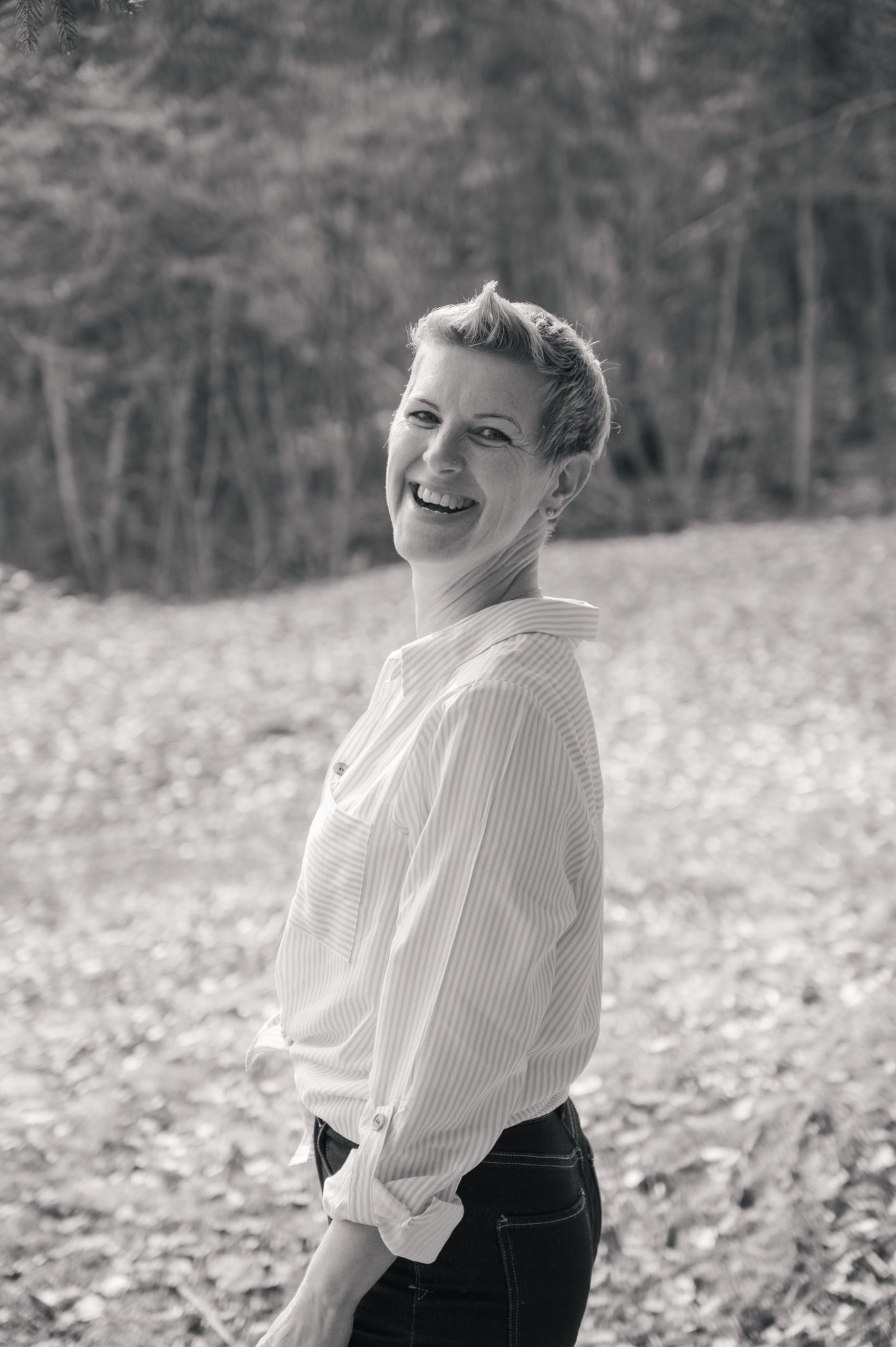 Black and white photo series showing a person in a white blouse and dark skirt laughing outdoors in a field.