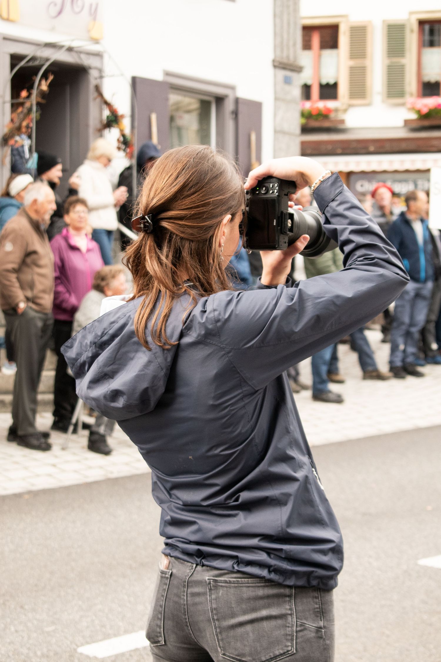 Photographer in blue jacket taking pictures at an outdoor event.
