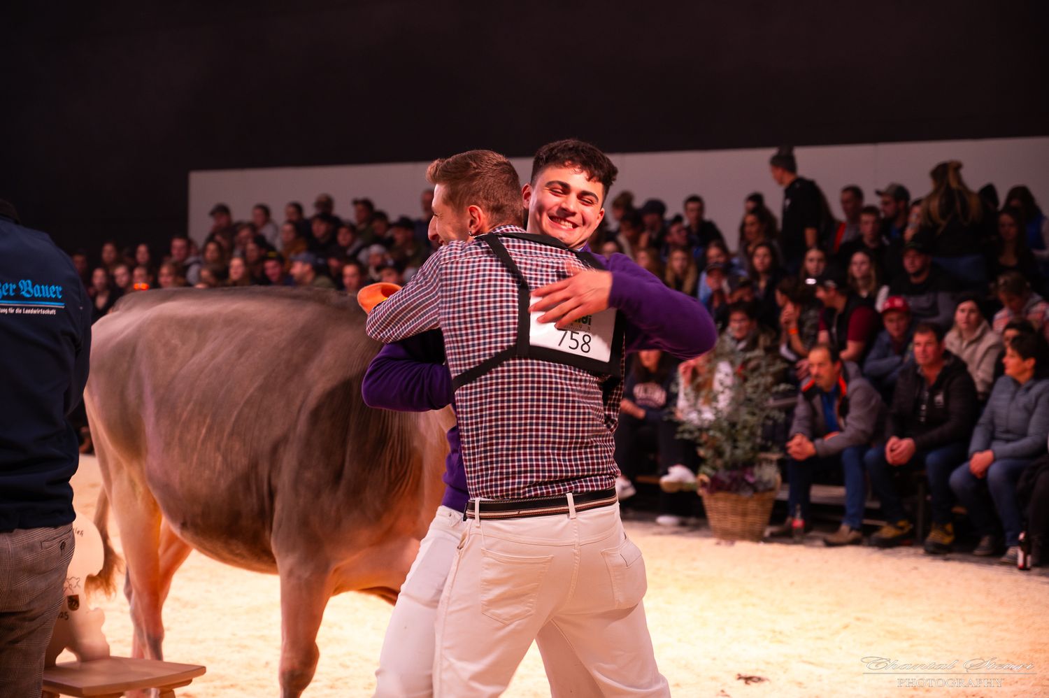 Celebratory moment during an indoor cattle show with audience in background.