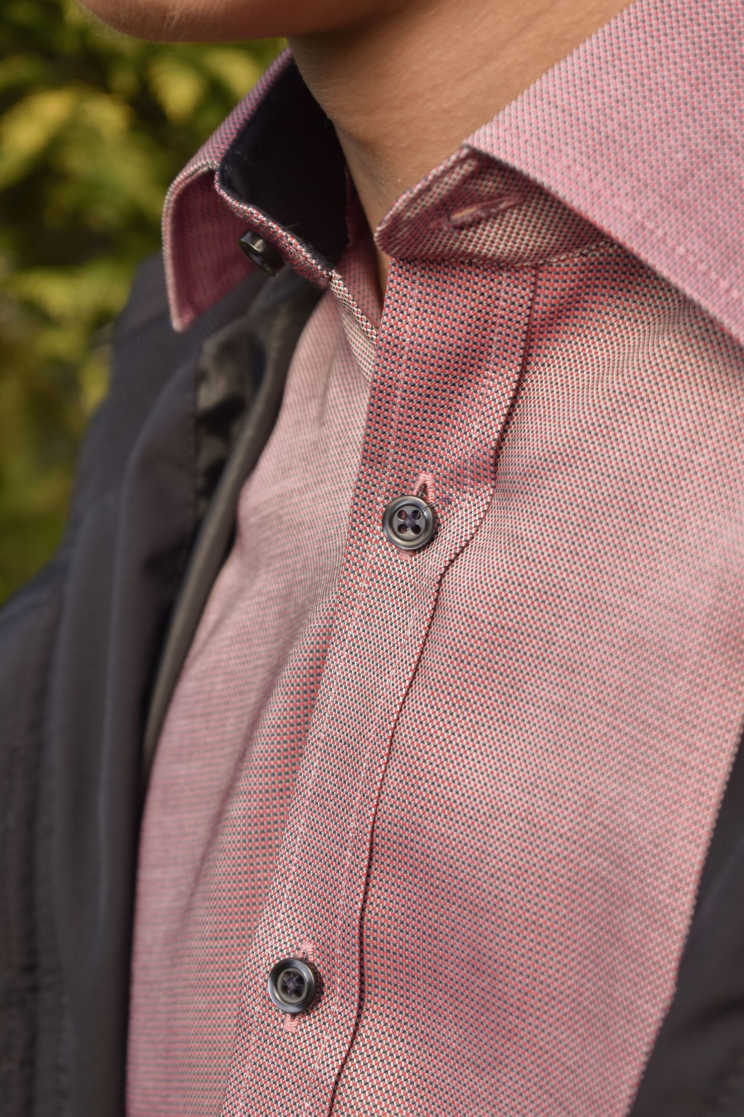 Close-up detail of a pink button-up dress shirt collar and buttons.