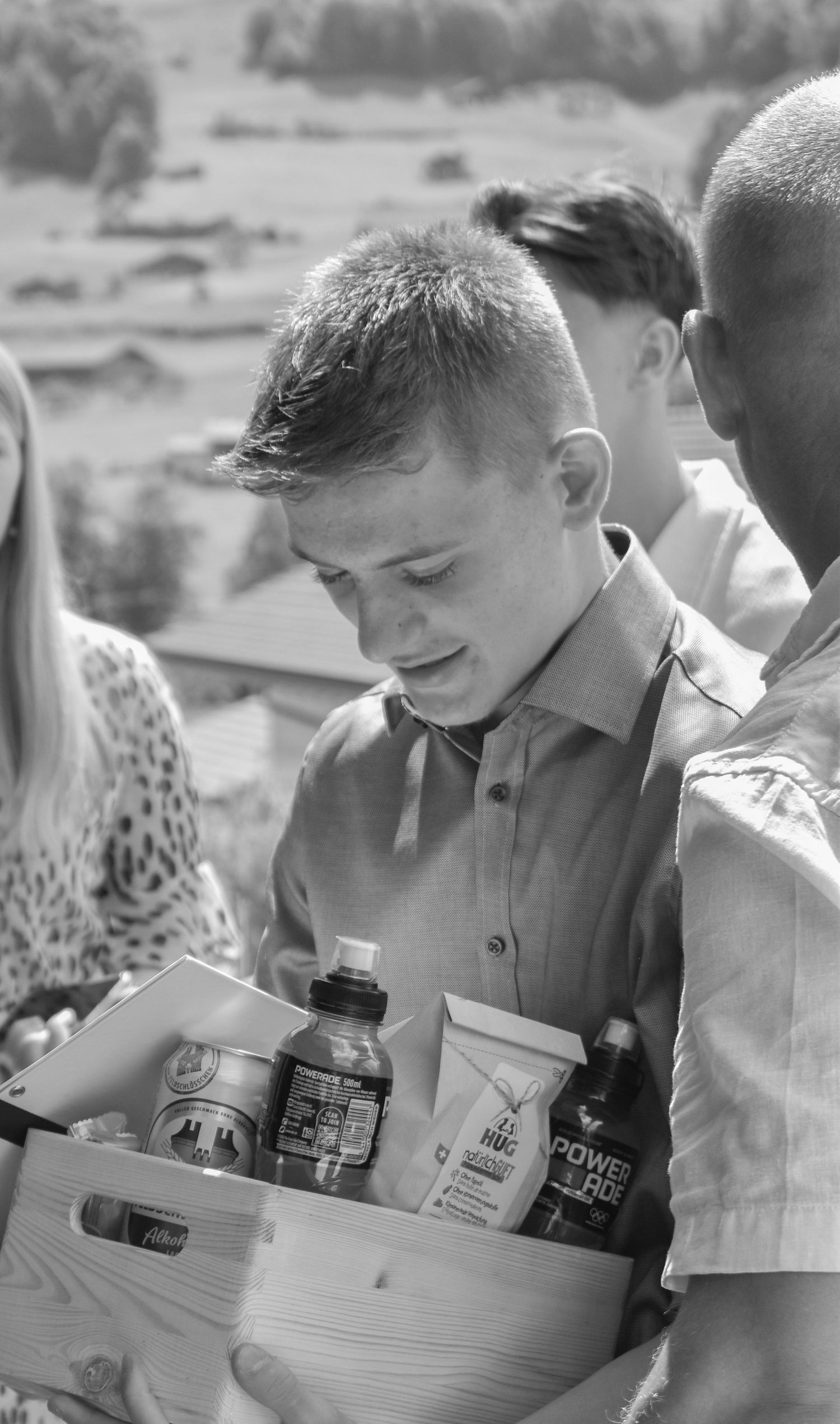 Black and white photo of people sitting at a table examining various bottles and containers in a vintage setting.