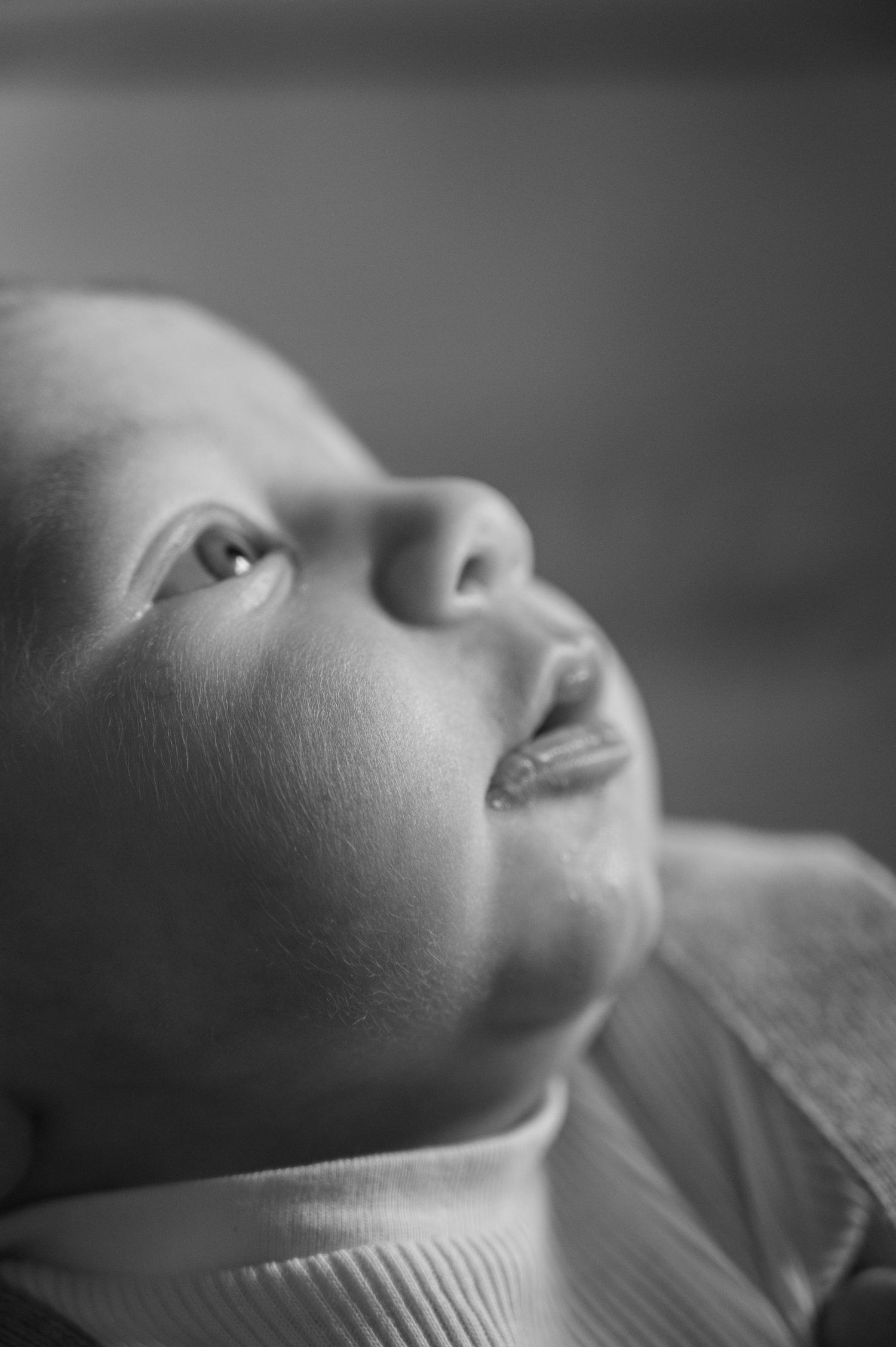 Black and white close-up of a baby's delicate features in soft light.