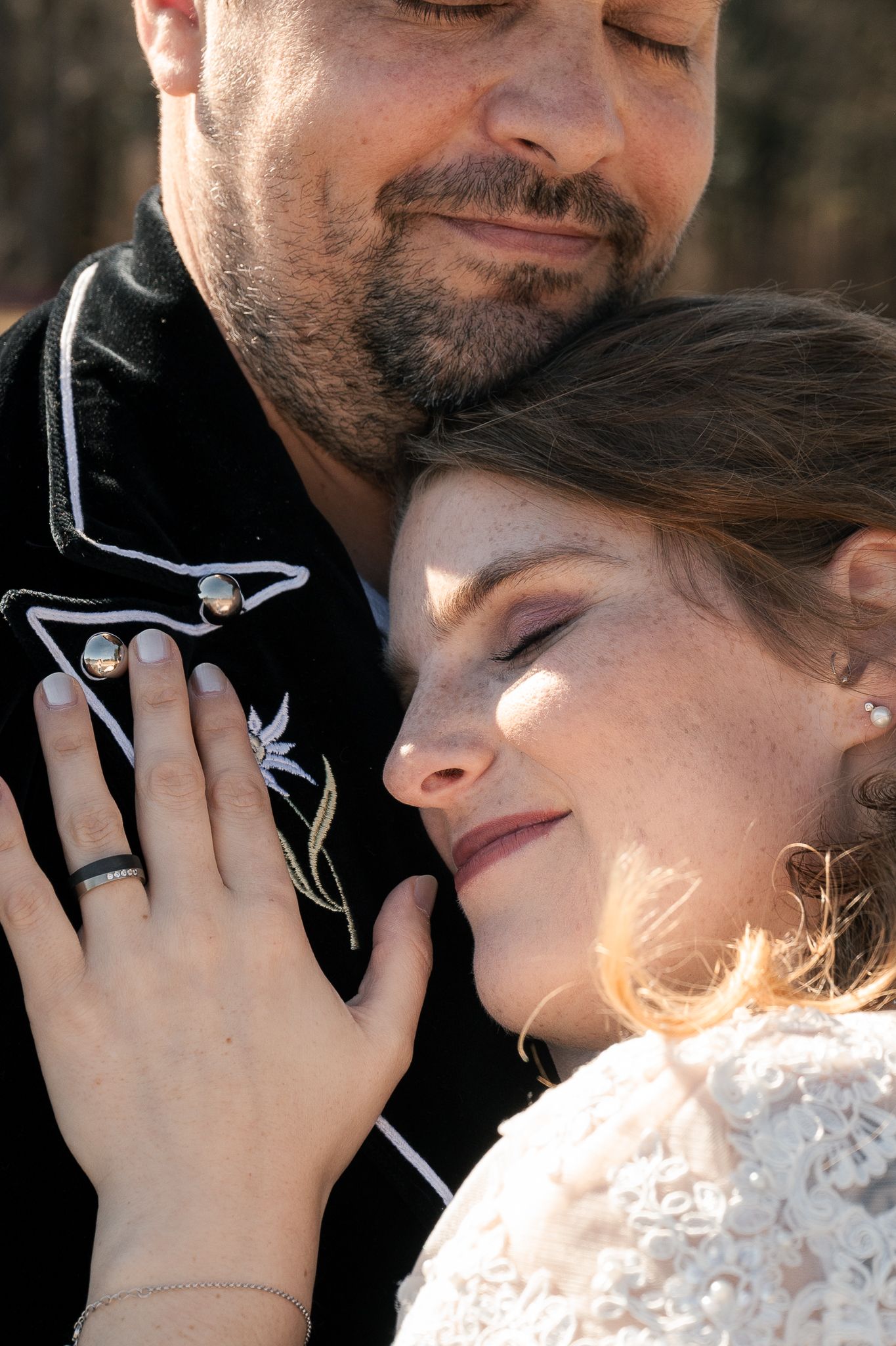 A romantic couple in winter clothing share an intimate moment as sunlight creates a warm glow around them.