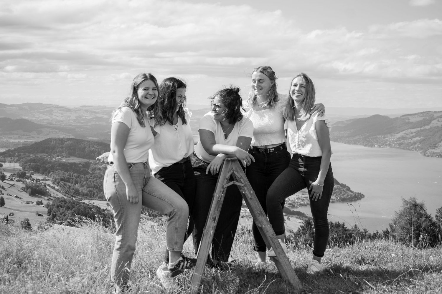Group enjoying scenic mountain views while sitting together on grassy hilltop.