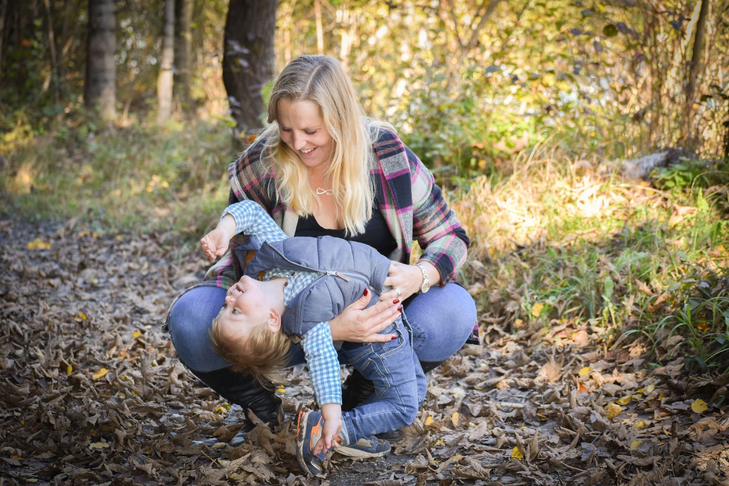Couple laying on autumn leaves in a forest during a romantic photoshoot.