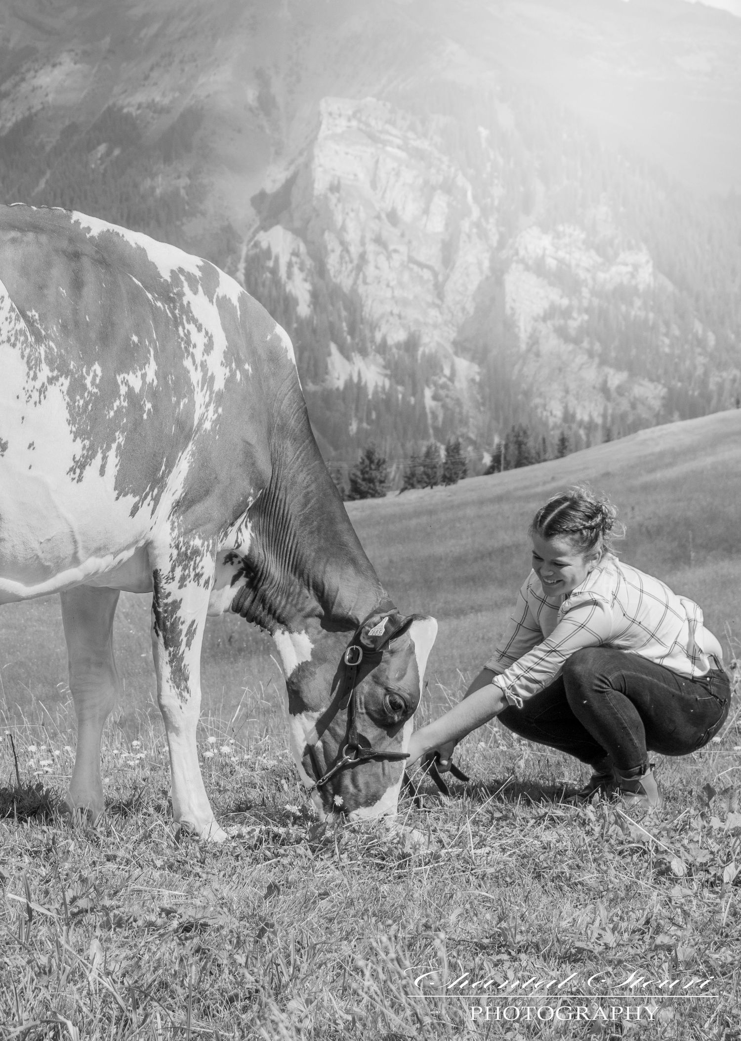 Black and white vintage photograph of people lying in alpine grass near mountain peaks.