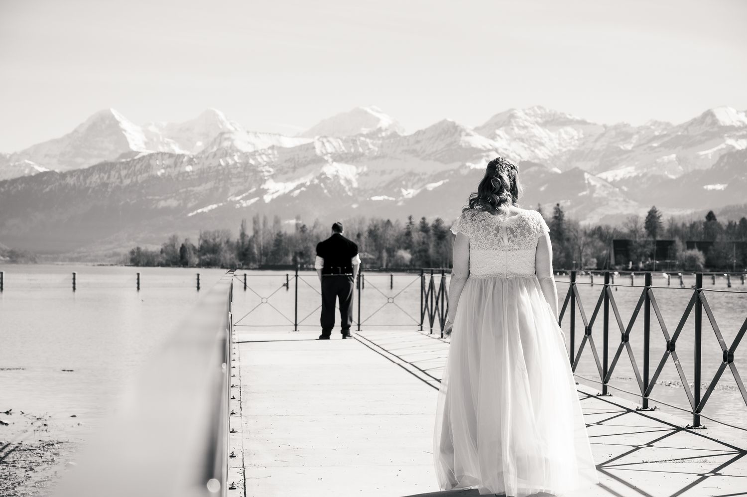 A scenic winter wedding photoshoot in a snowy mountain landscape with snow-capped peaks in the background.