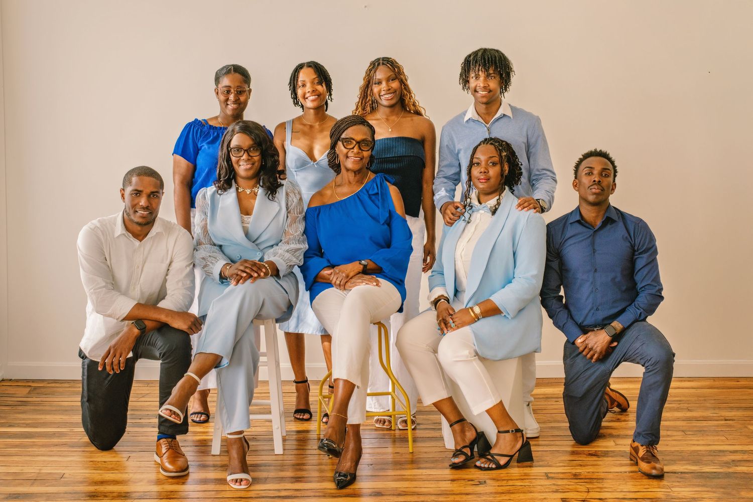 Group of people sitting together on a wooden floor wearing coordinated blue and white casual outfits.