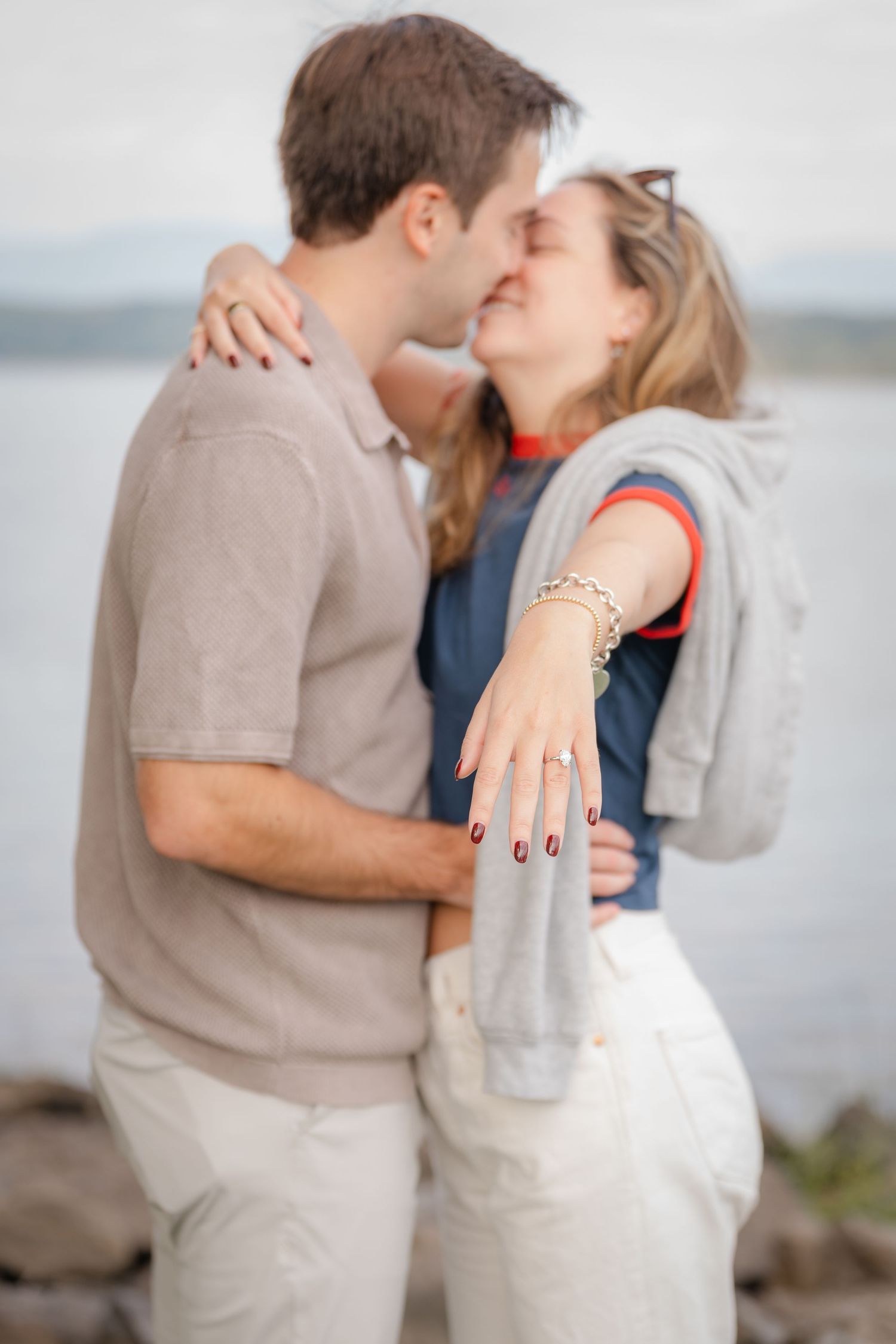 A romantic couple embraces and kisses on a misty beach in a series of intimate engagement photos.