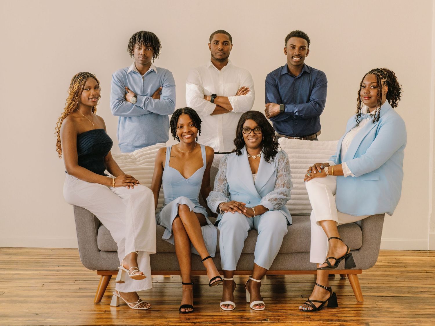 A group sits together on a light gray couch wearing coordinated blue and white outfits for a casual family photo.