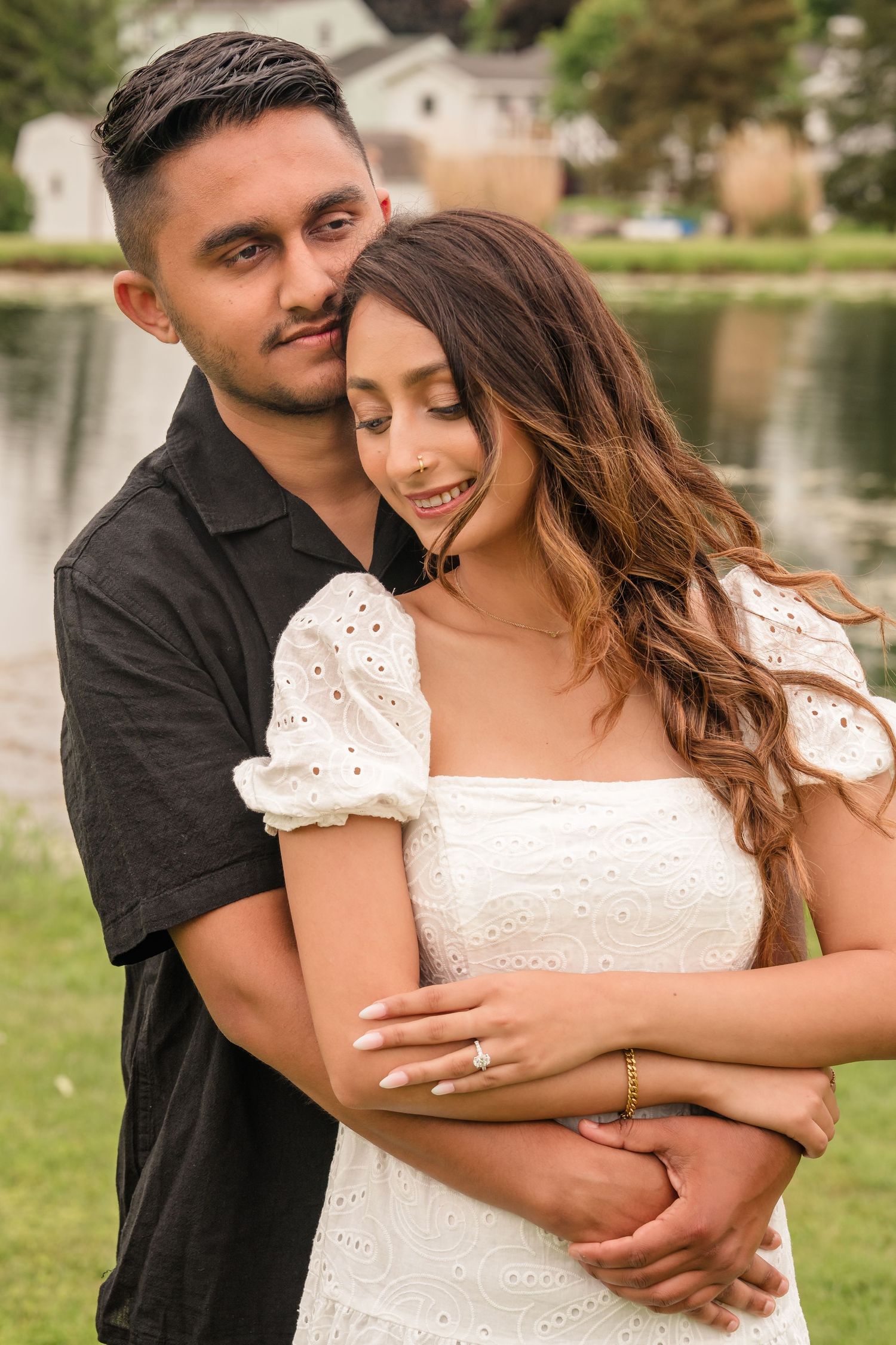 A tender moment captured between a couple wearing black and white outfits in an outdoor setting.