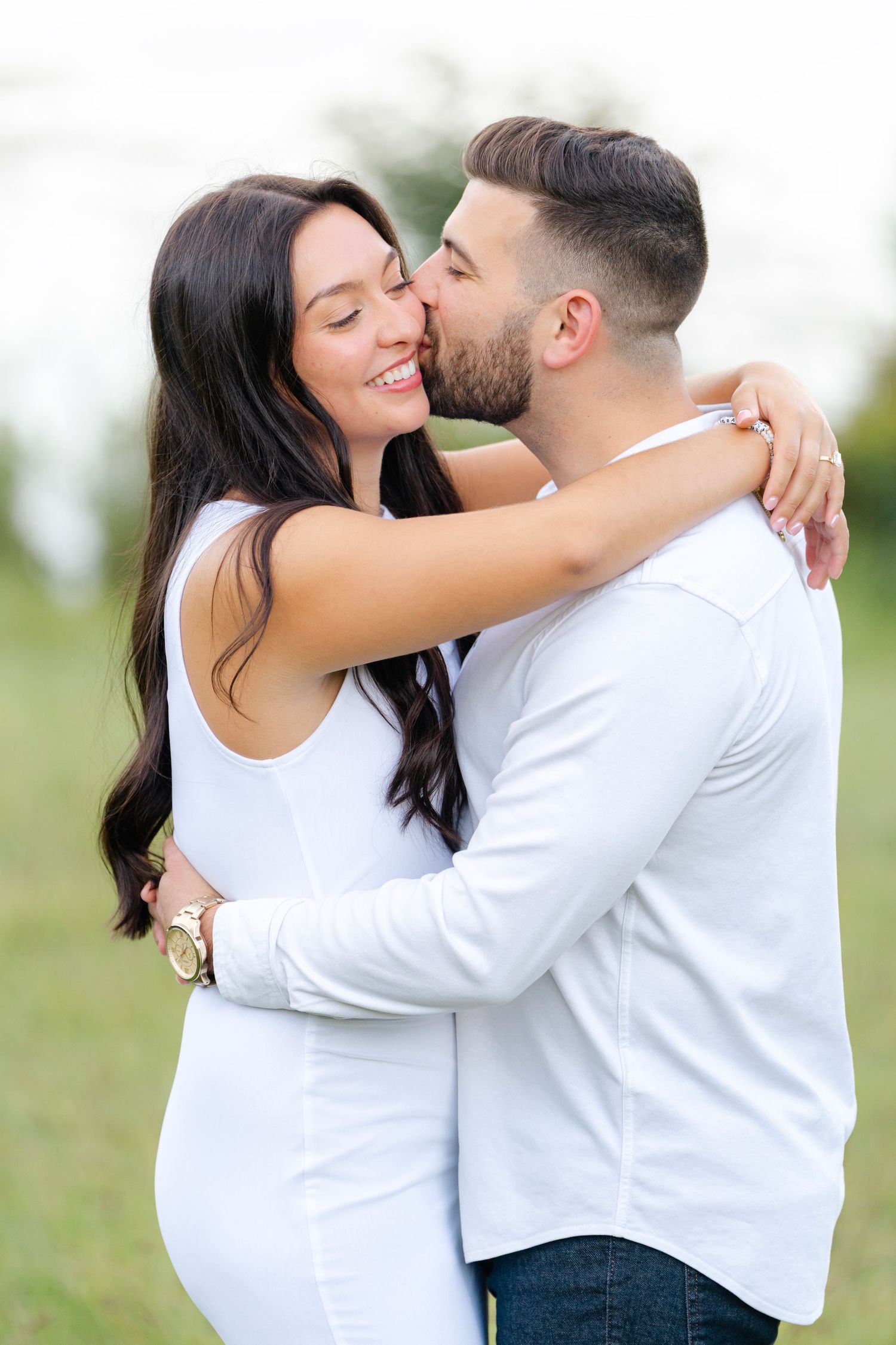 An intimate series of embraces between a couple wearing white against a natural outdoor backdrop.