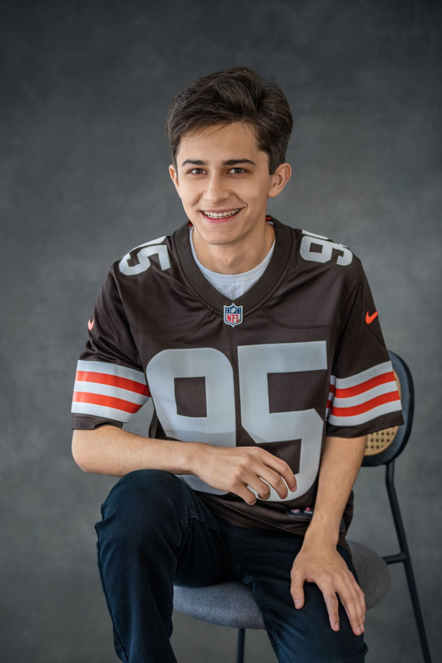 High school senior in a Cleveland Browns NFL jersey poses casually in a studio portrait setting.