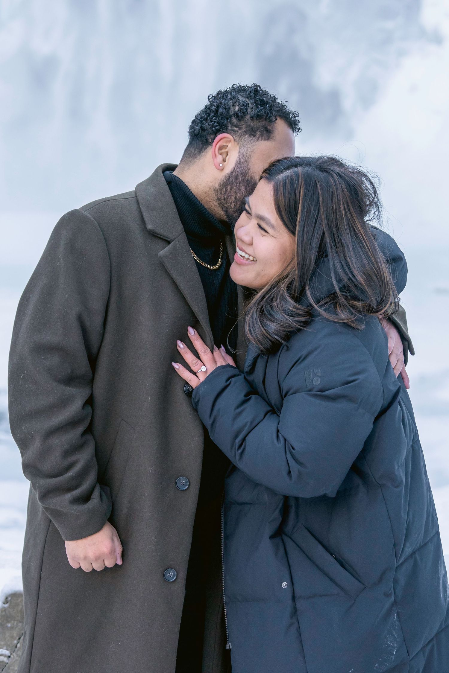 A couple in winter coats share intimate moments and laughter in a series of romantic poses against a snowy background.