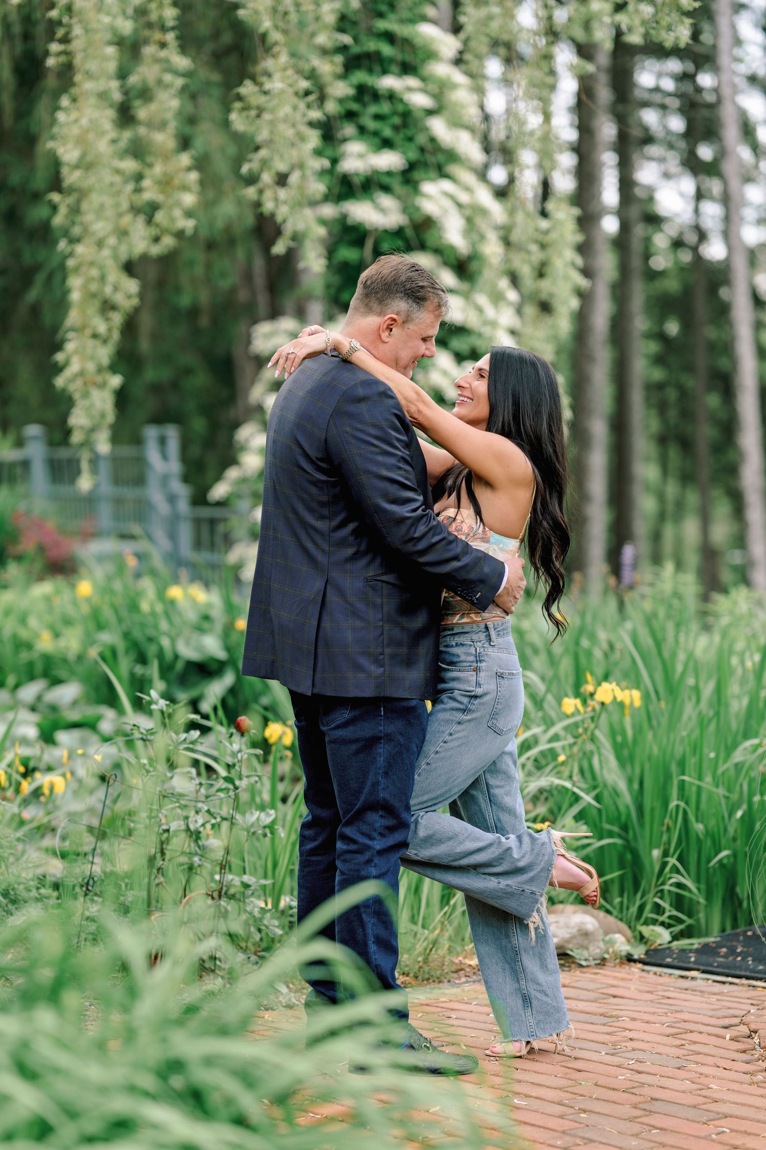 Romantic couple sharing tender moments on a brick path surrounded by spring flowers.
