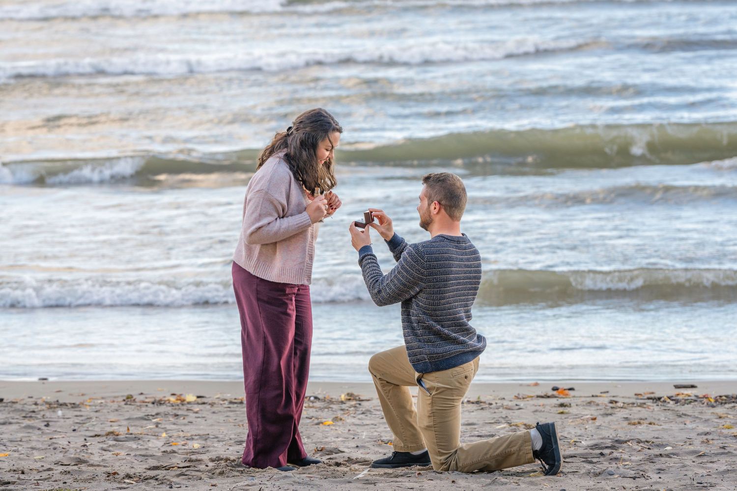 A romantic beach proposal sequence showing a couple on a sandy shore with waves in the background.