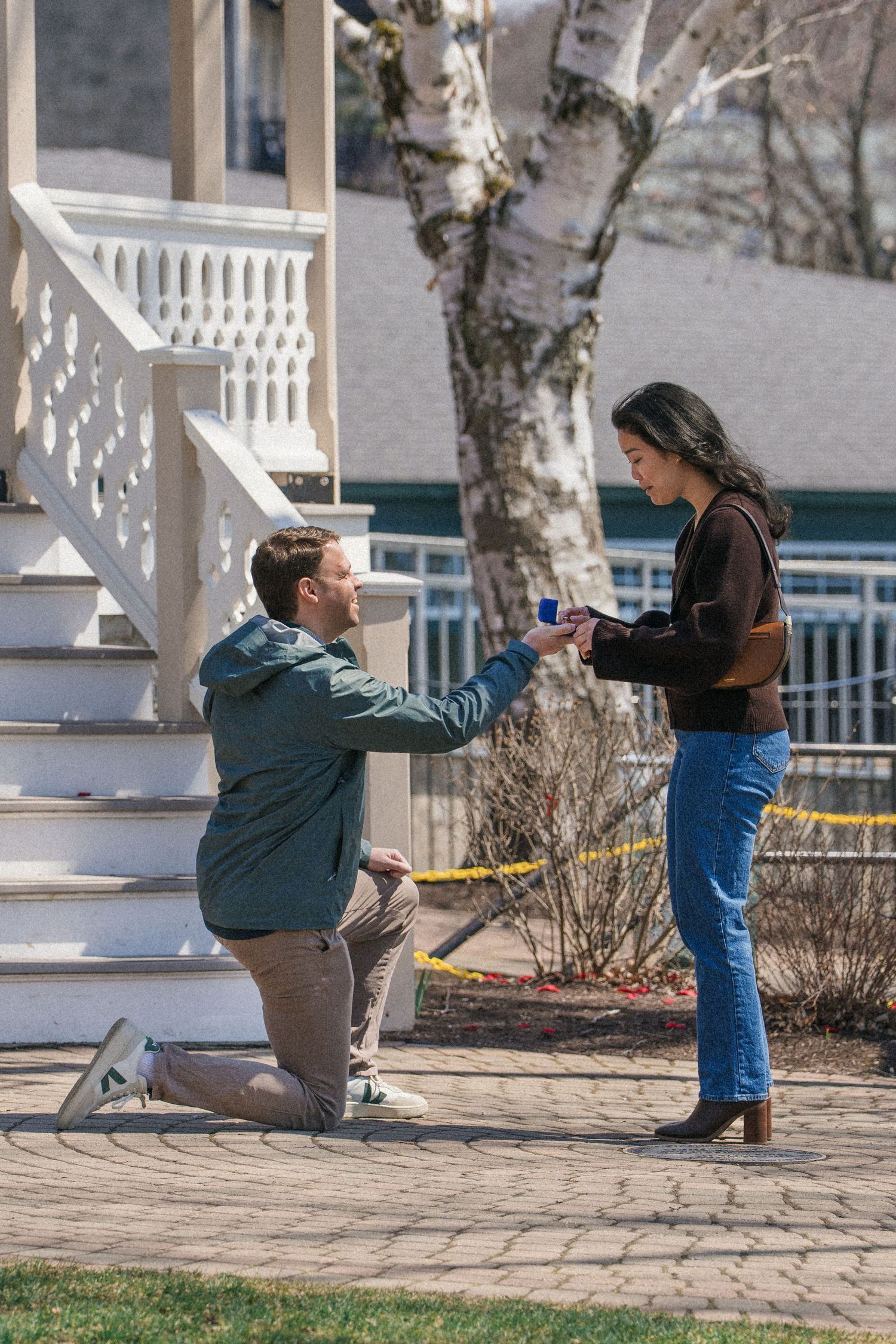 A proposal sequence showing a surprise engagement on a stone patio with birch trees in the background.