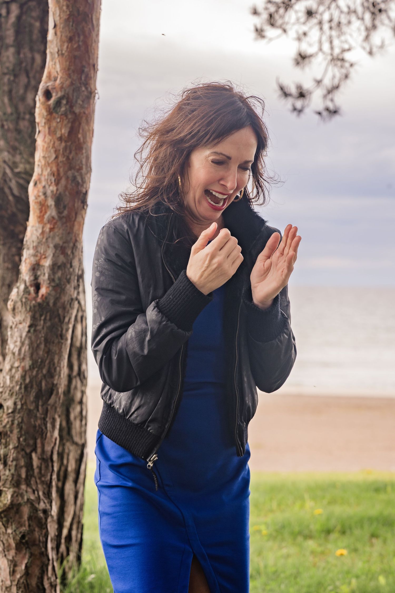 A series of candid outdoor photos showing someone laughing joyfully in a blue top and black jacket against a natural backdrop.