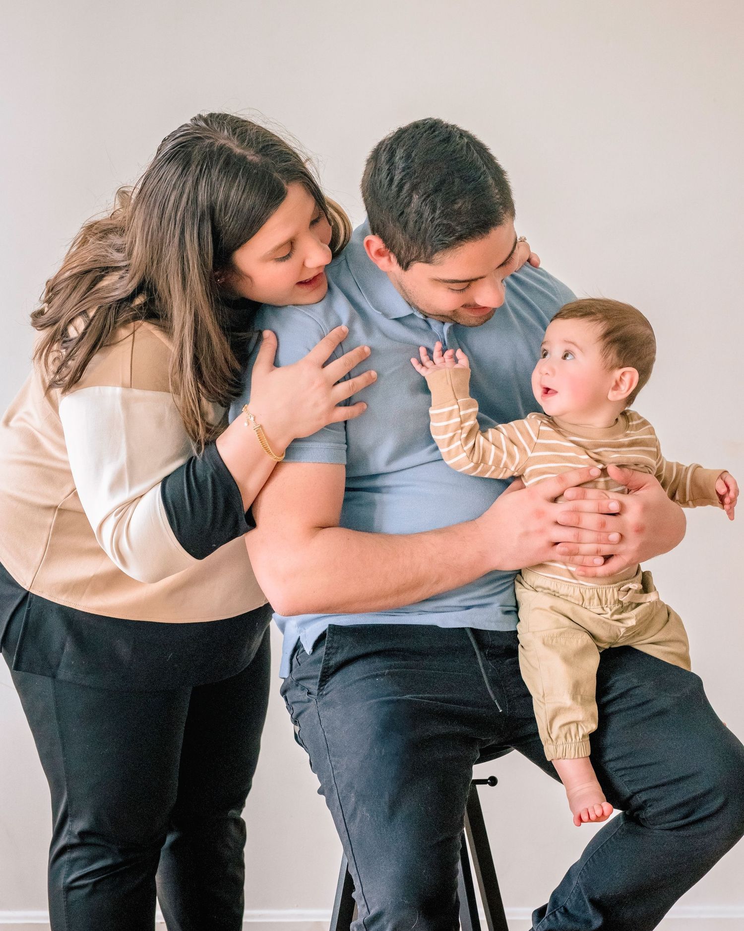Young family portrait with mother, father, and baby in studio.