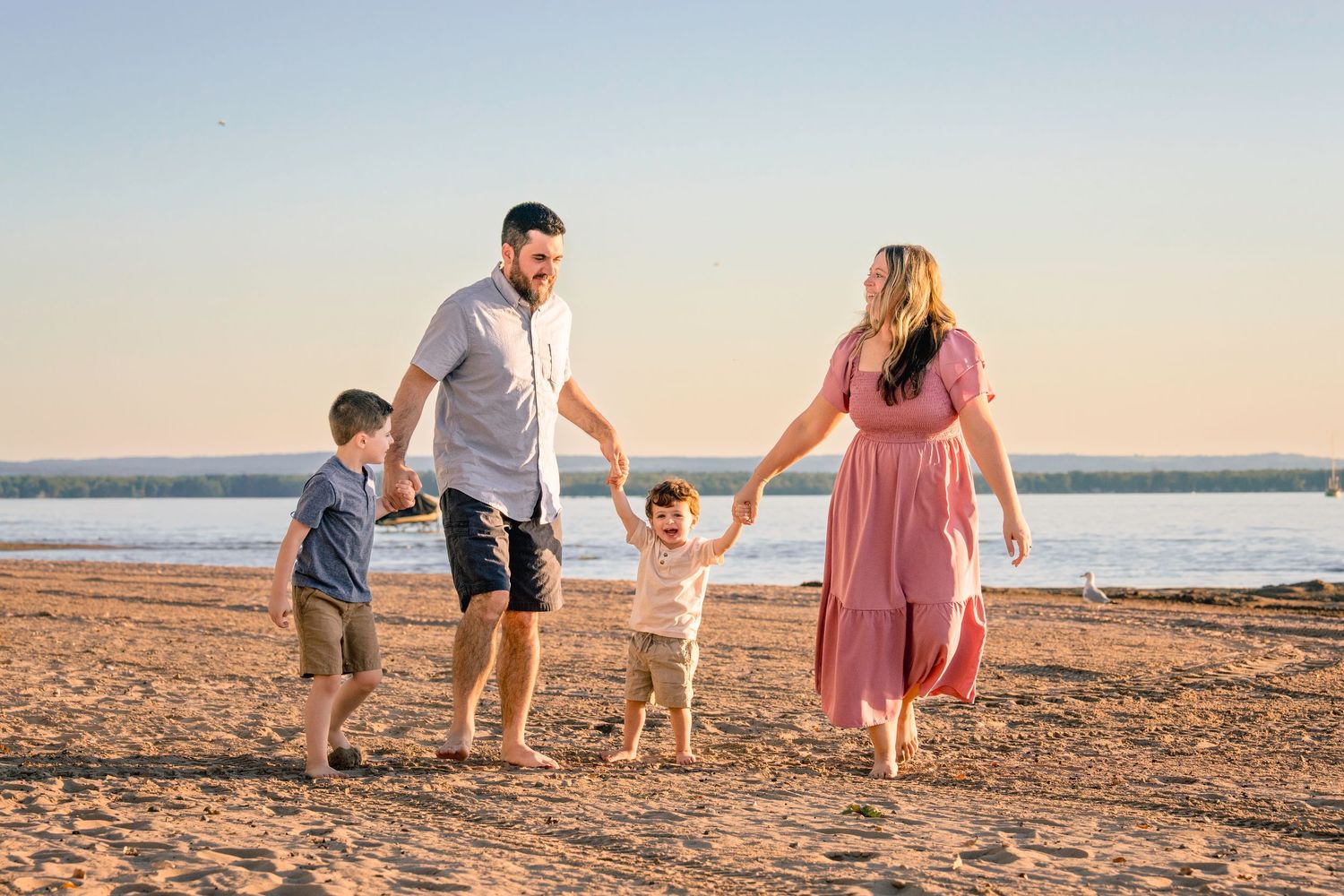 Family enjoying a sunset walk together along a sandy beach during golden hour.