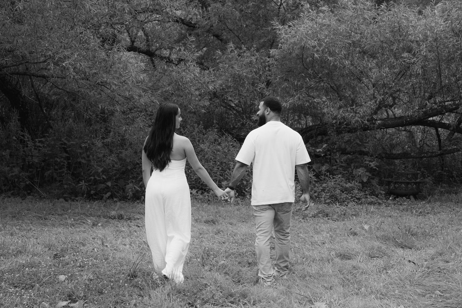 A series of black and white photos showing two people walking together through a park or wooded area.