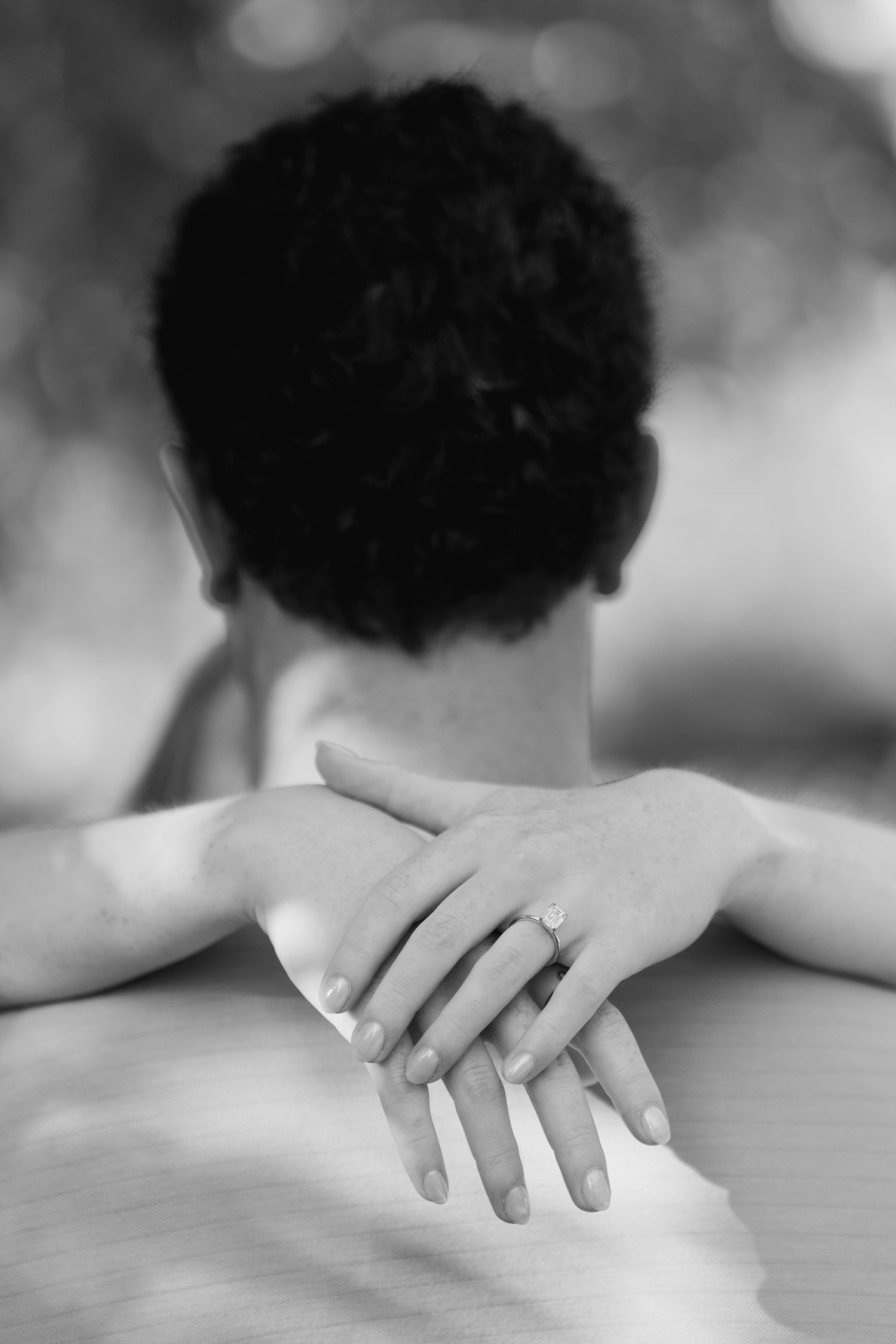 Close-up black and white image showing hands gently resting on a surface.