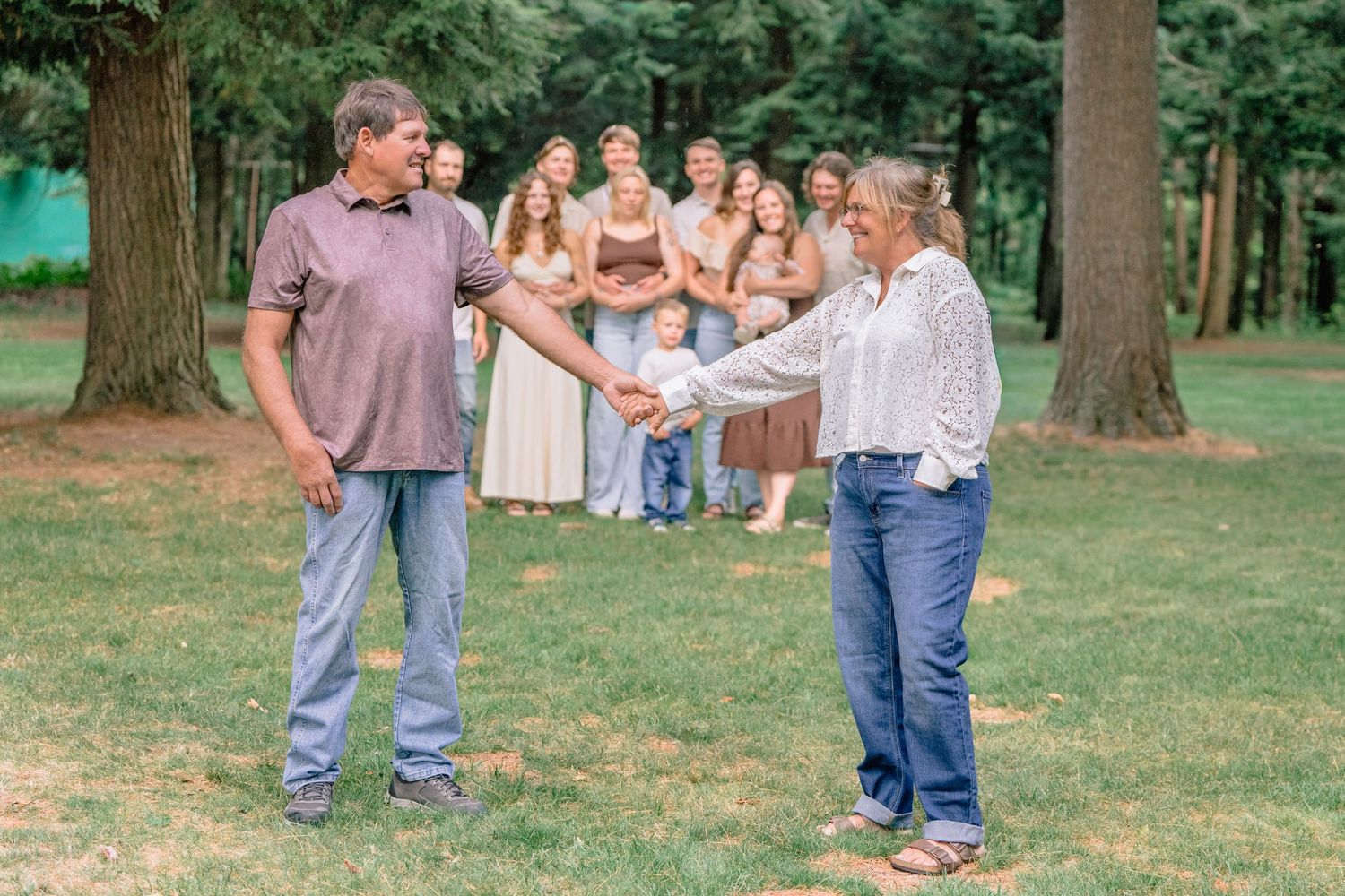 A group gathers outdoors for a ceremony in a wooded setting on a sunny summer day.