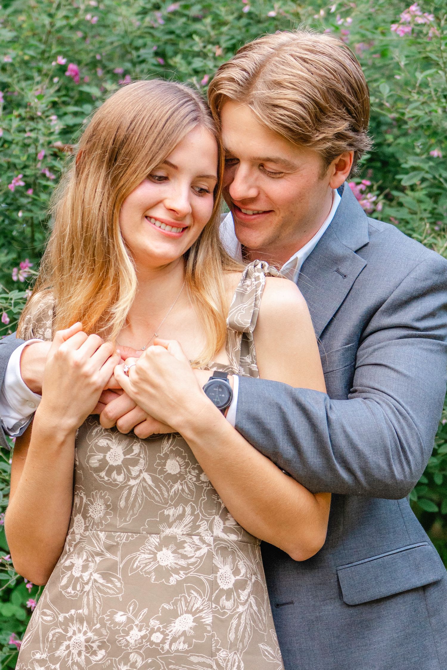 A romantic couple shares tender moments in a garden setting while wearing formal attire and embracing.