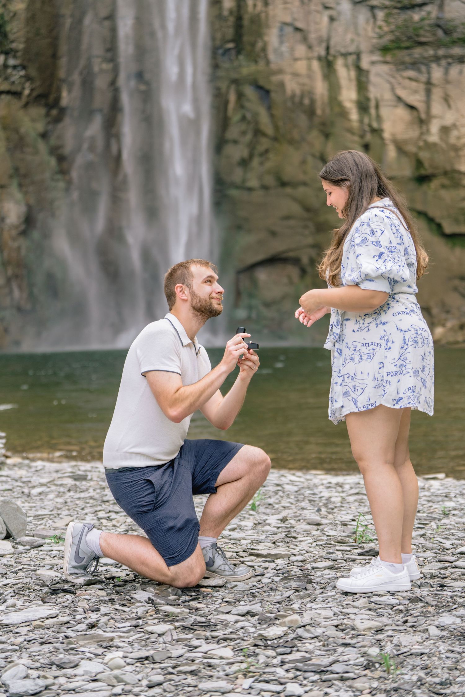 A romantic proposal sequence by a waterfall showing five progressive moments of a couple on rocky terrain.