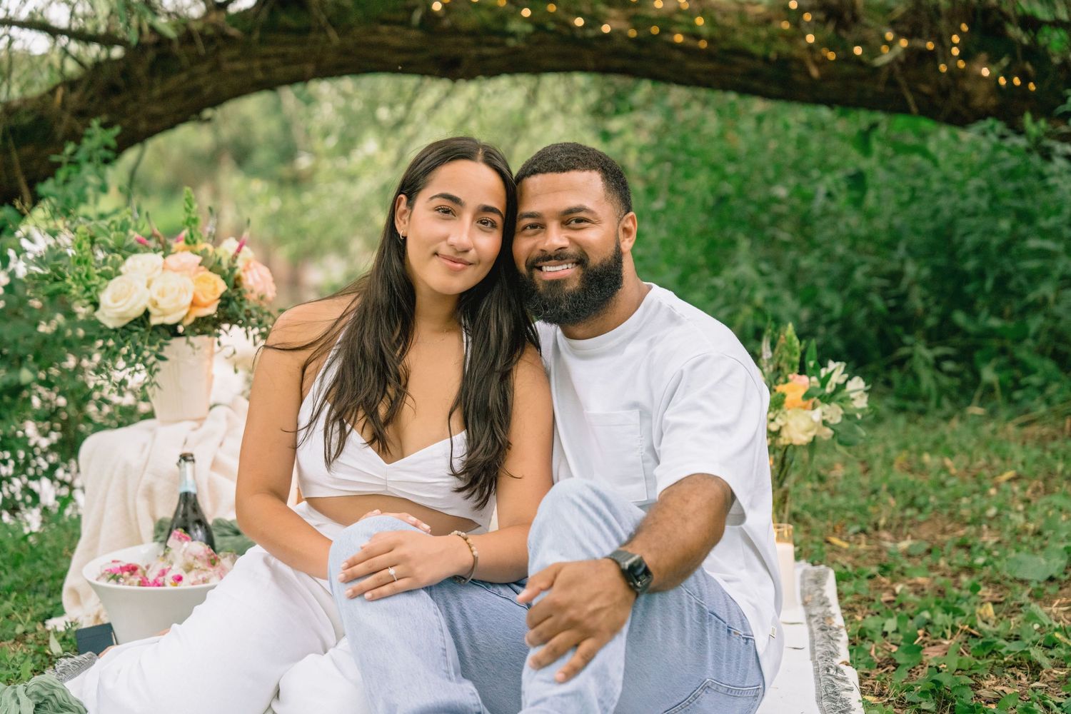A romantic outdoor photoshoot in a lush green park setting with soft natural lighting and white attire.