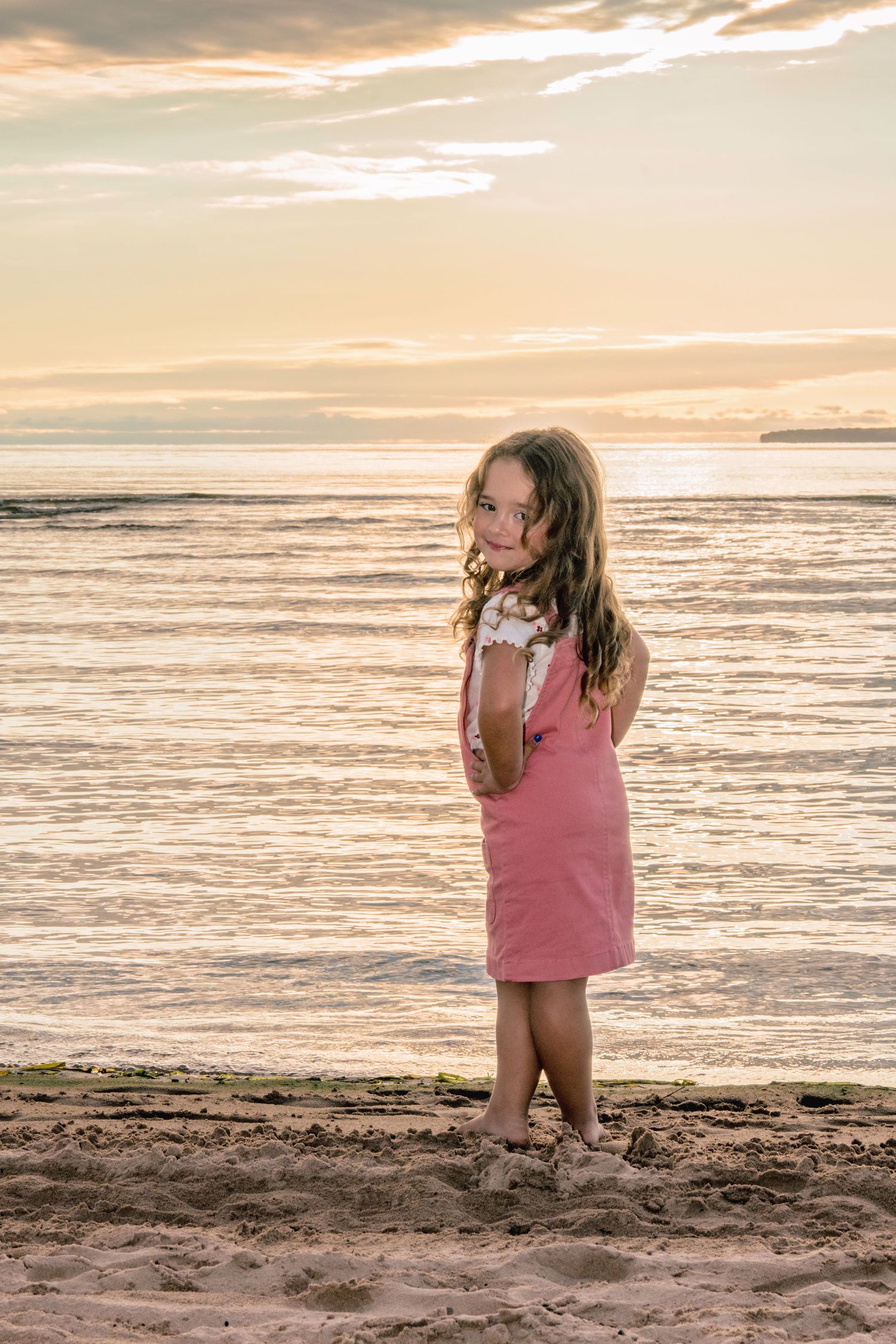 A peaceful beach scene at sunset with gentle waves rolling onto the shore in warm golden light.