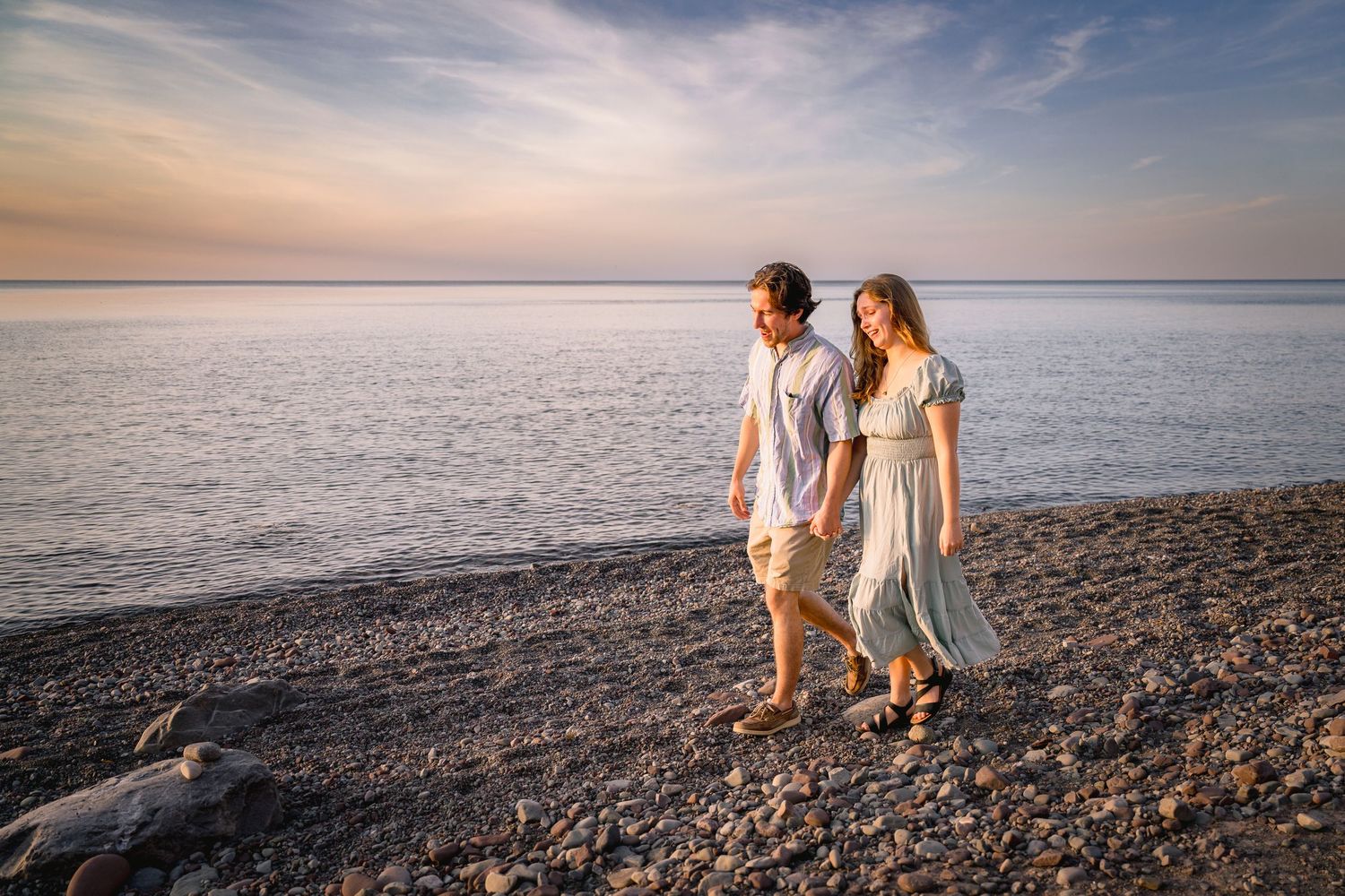 Scenic beach engagement photoshoot with dramatic sunset sky and rocky shoreline.