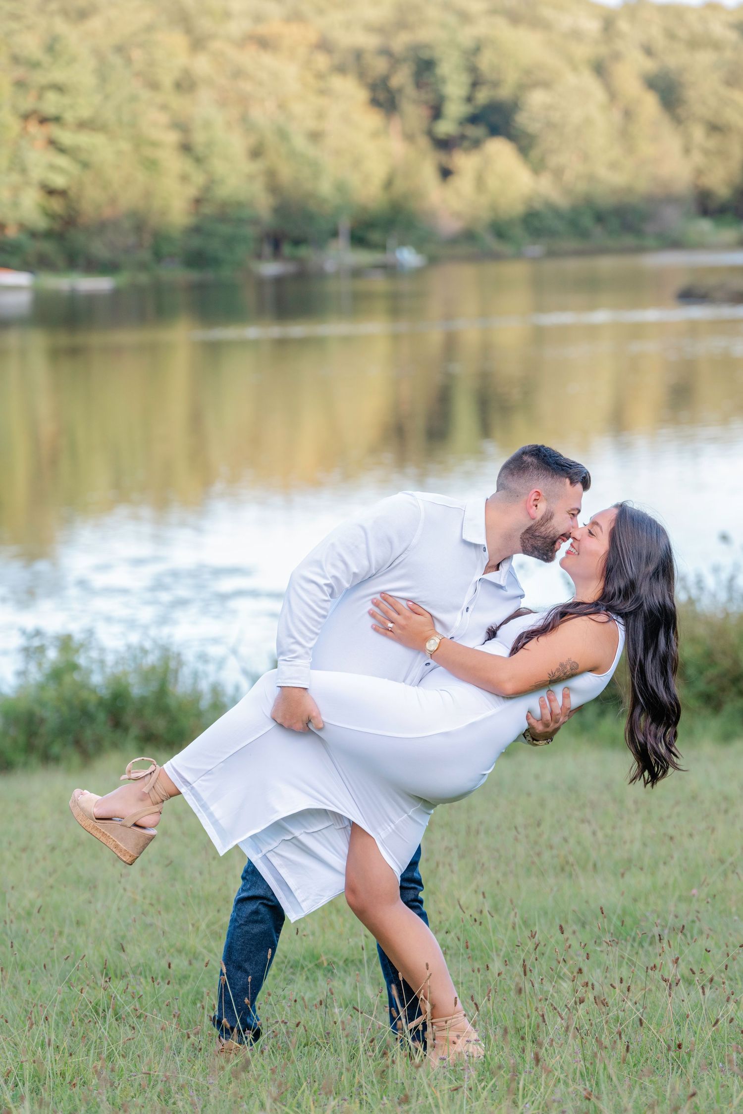 A romantic dip pose sequence captured by a lake with the couple in matching white outfits.