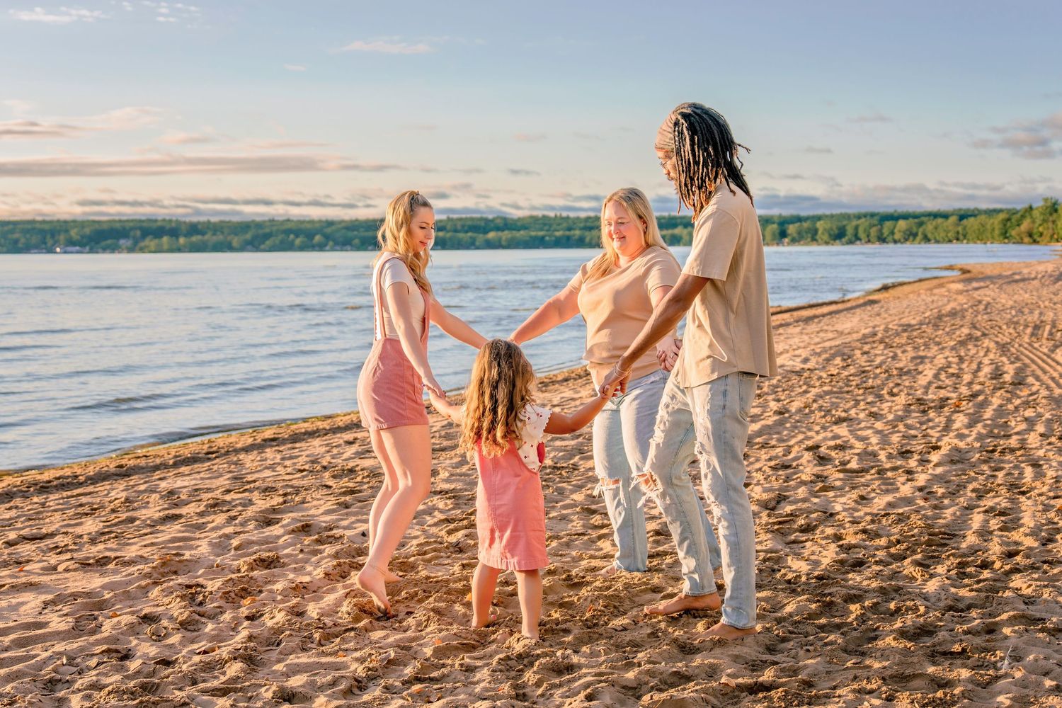 A group of people walking together on a sandy beach at sunset, holding hands and enjoying the ocean view.
