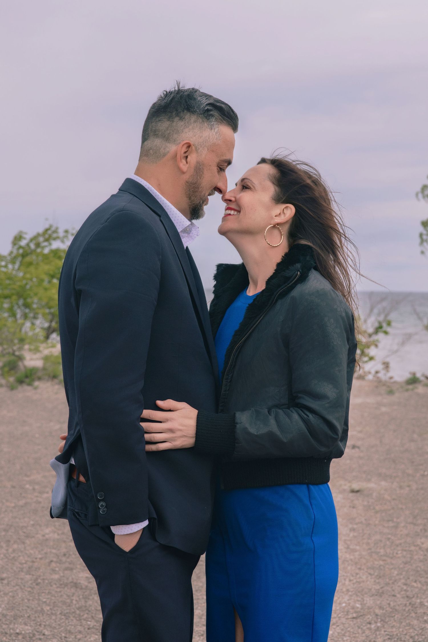 A romantic series of candid moments between a couple embracing outdoors against an overcast sky.