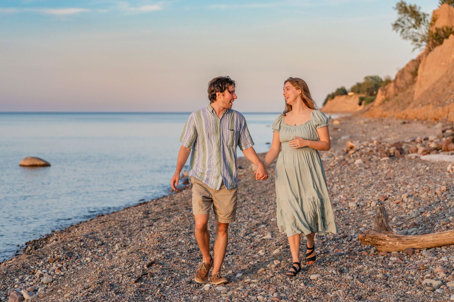 Couple walking together on a rocky beach at sunset holding hands along the Mediterranean coastline.