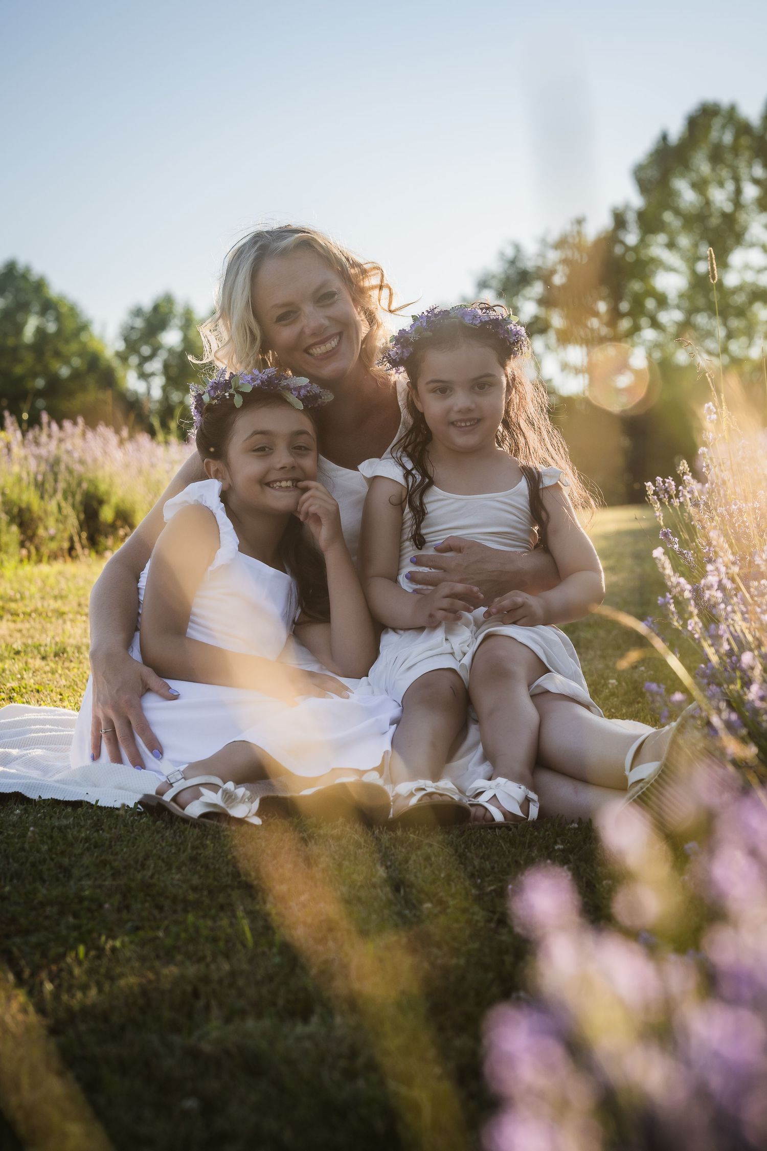 A heartwarming family moment captured in a sunlit field with blooming pink flowers during golden hour.