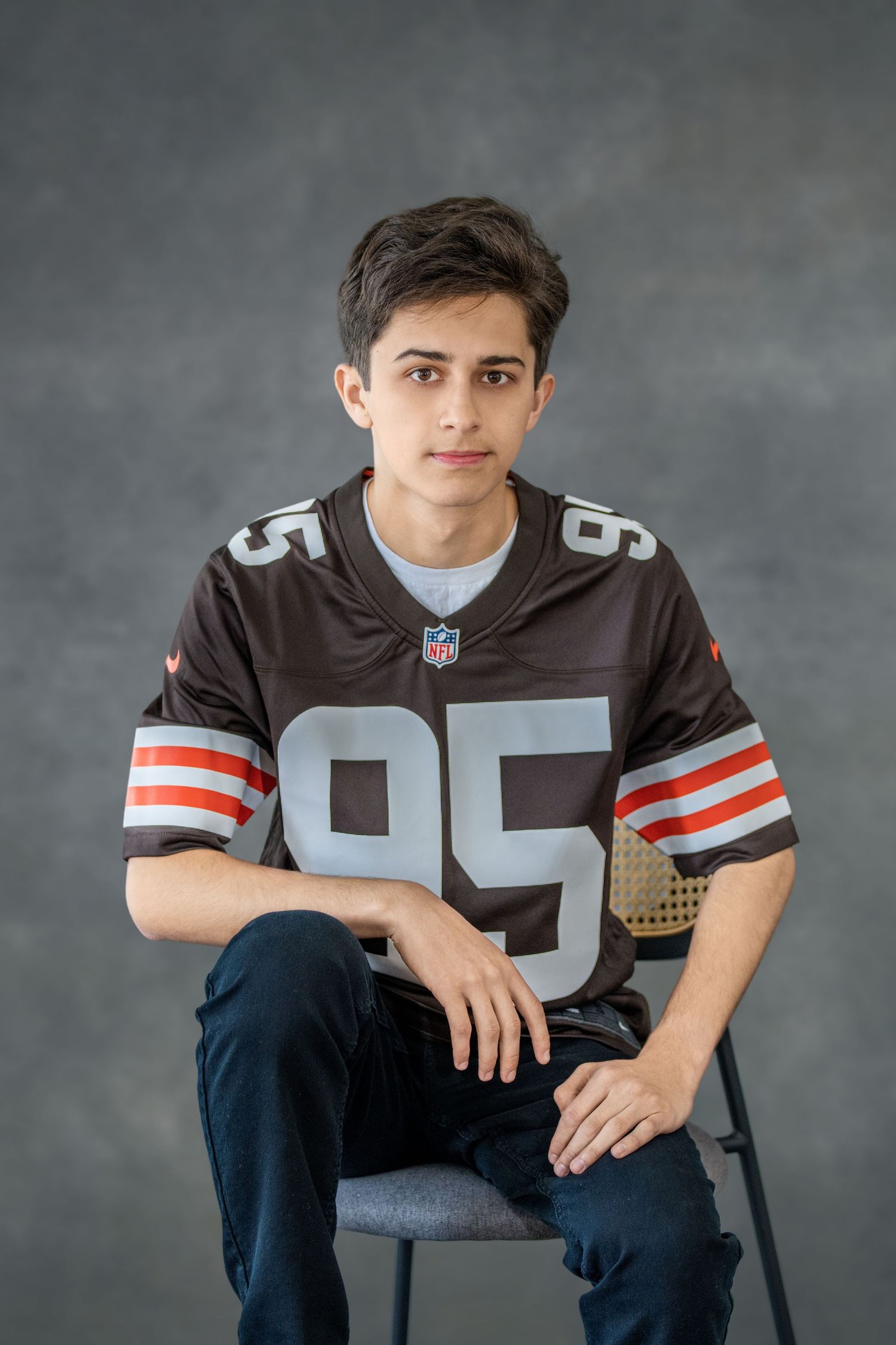 High school senior wearing NFL jersey number 95 poses casually in studio portrait session.